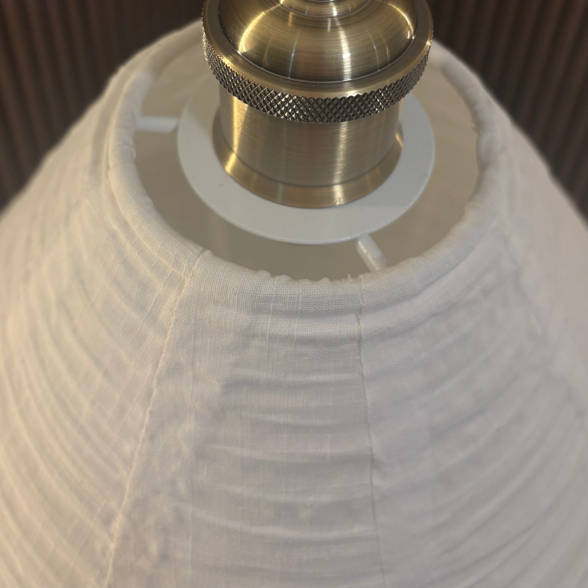 Close-up of a lamp with a white shade and brass fitting.