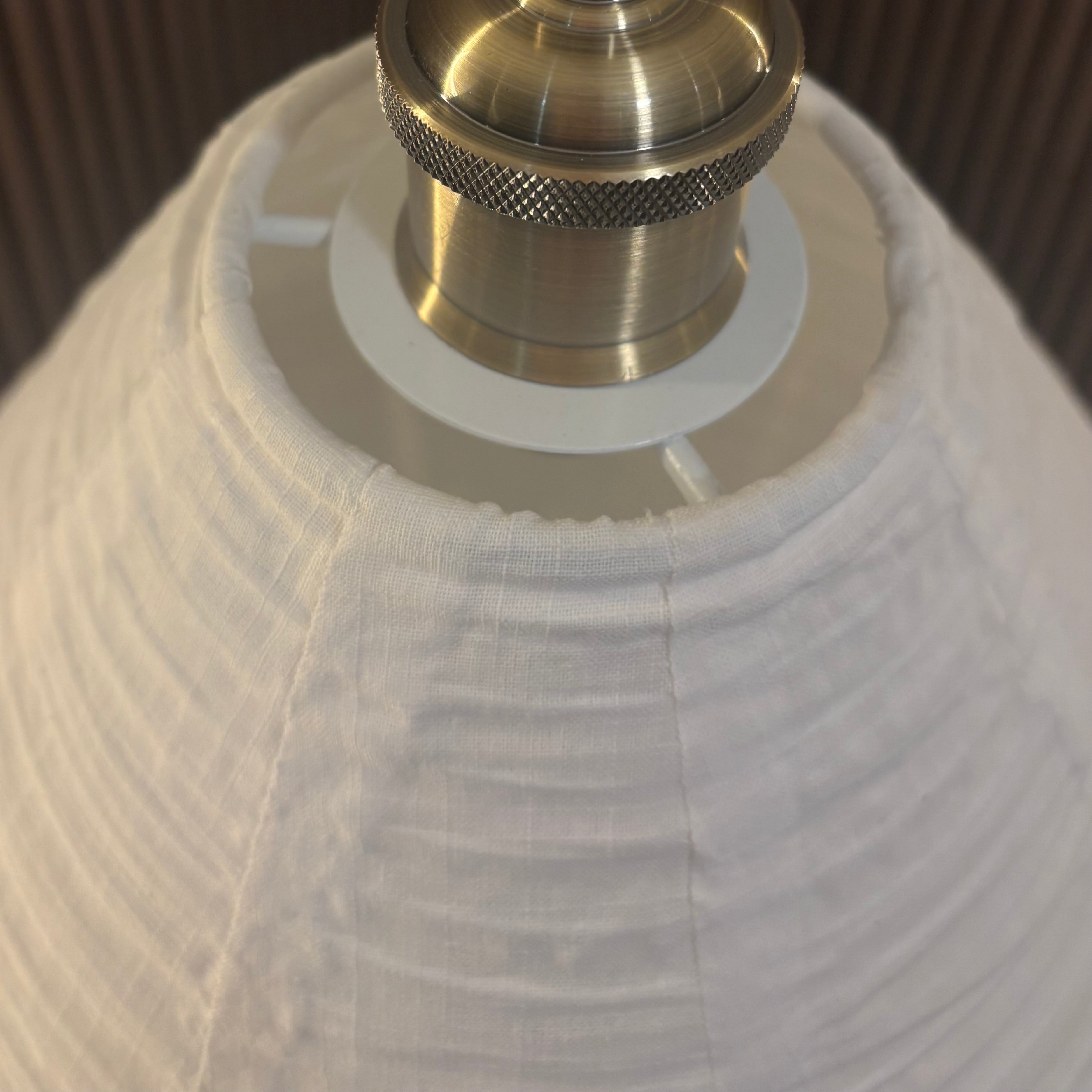 Close-up of a lamp with a white shade and brass fitting.