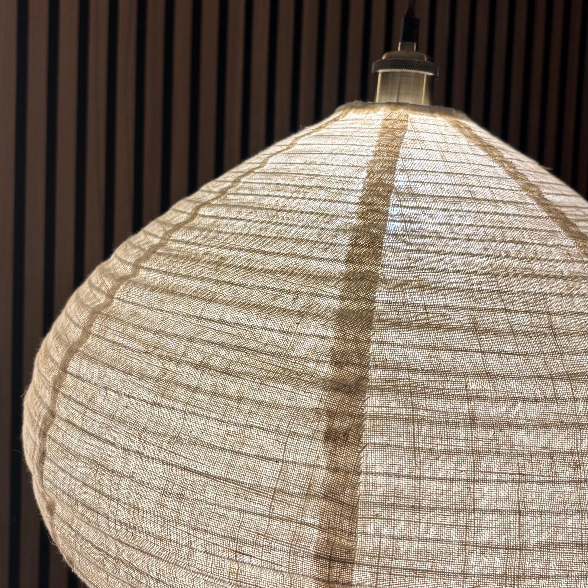 Textured pendant light hanging against a dark wooden panel background