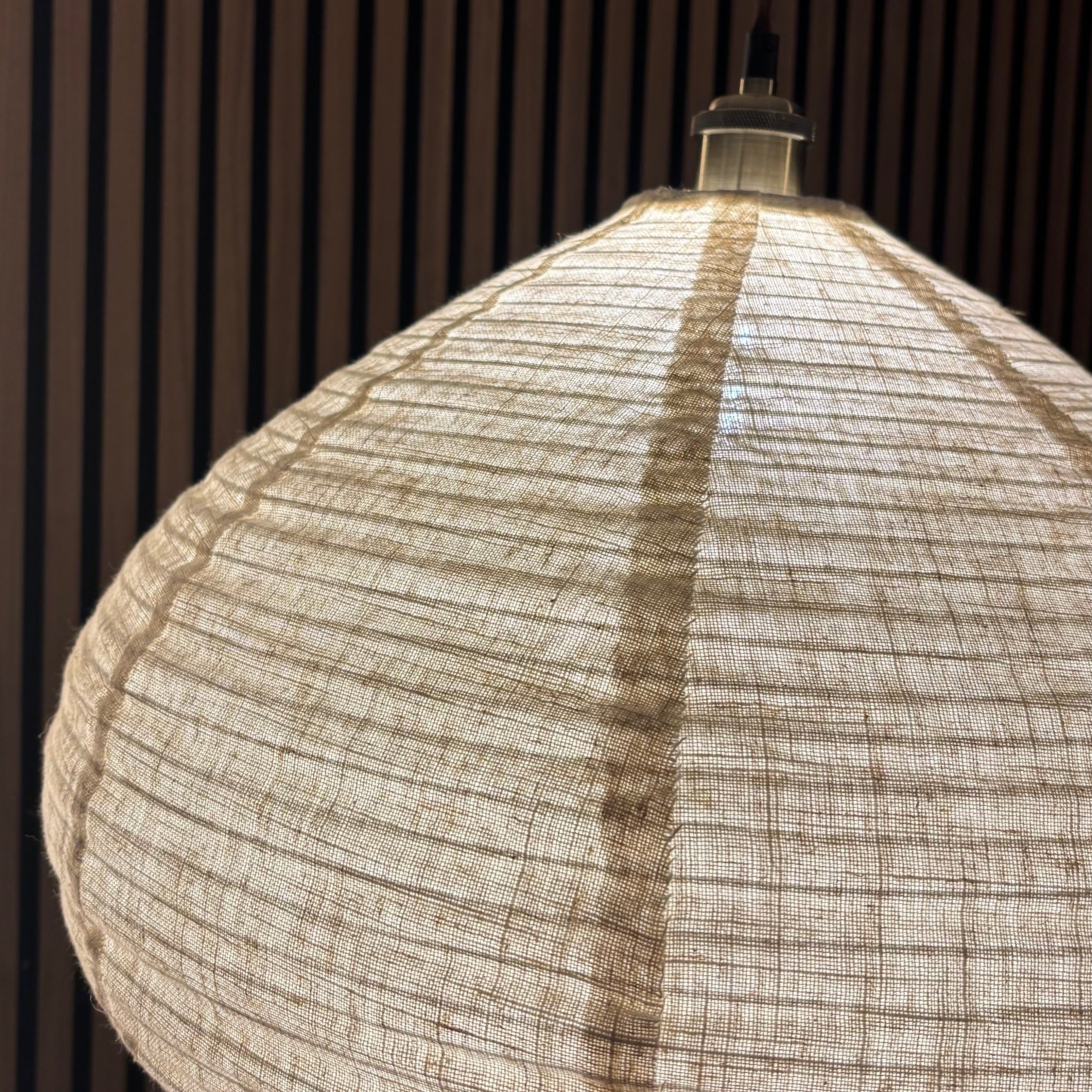 Textured pendant light hanging against a dark wooden panel background