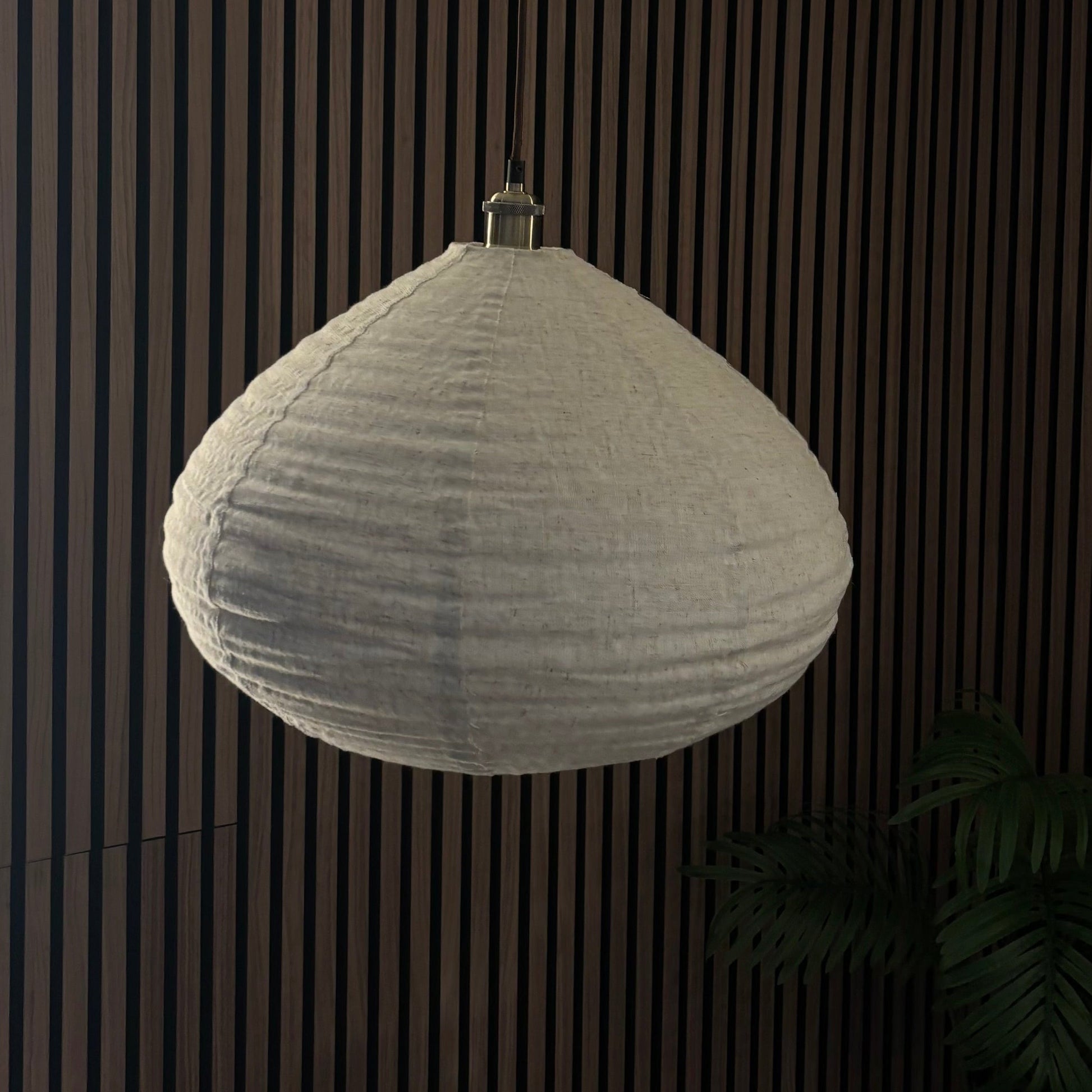 Textured pendant light hanging against a dark wooden panel background