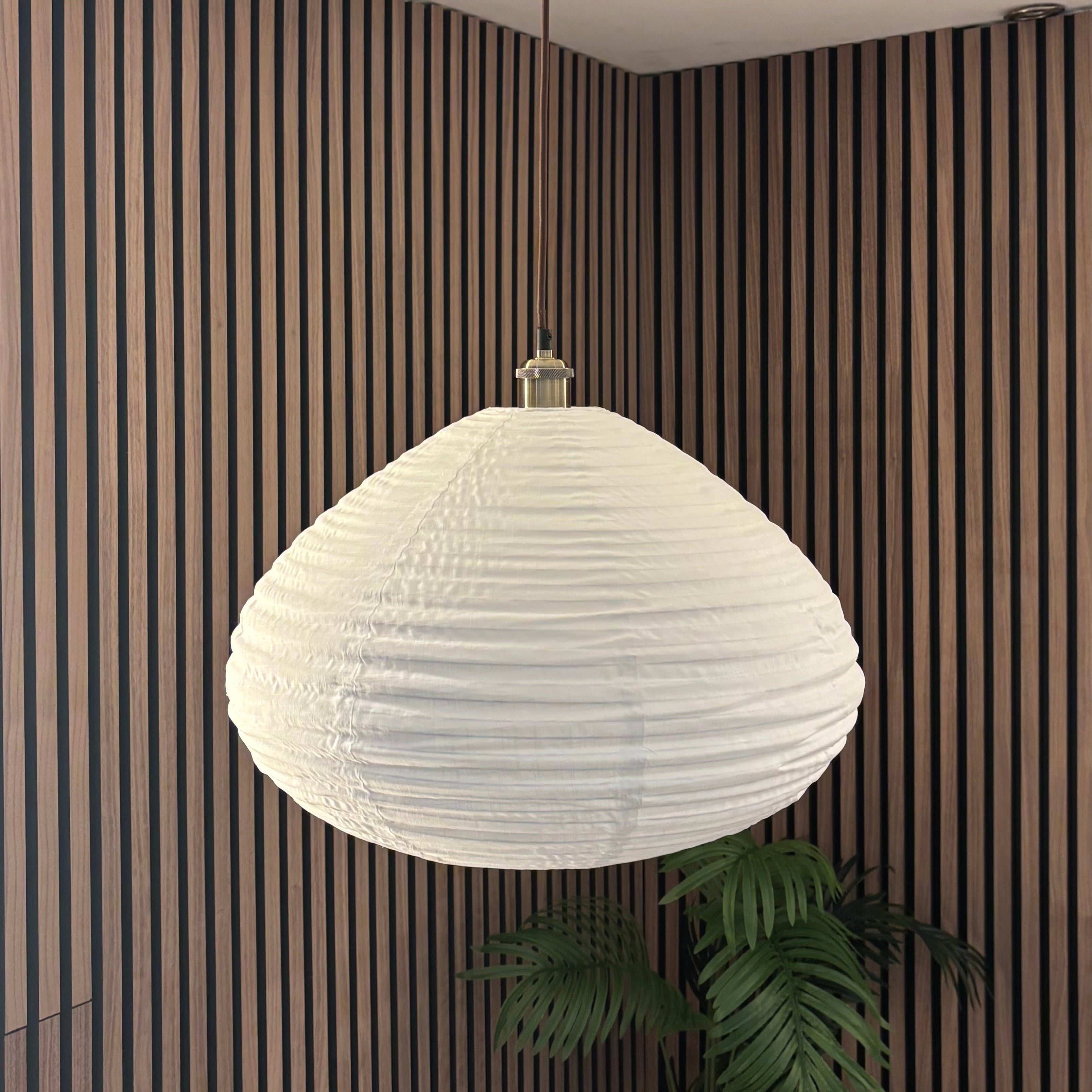 White pendant light hanging from a ceiling in a room with striped walls.