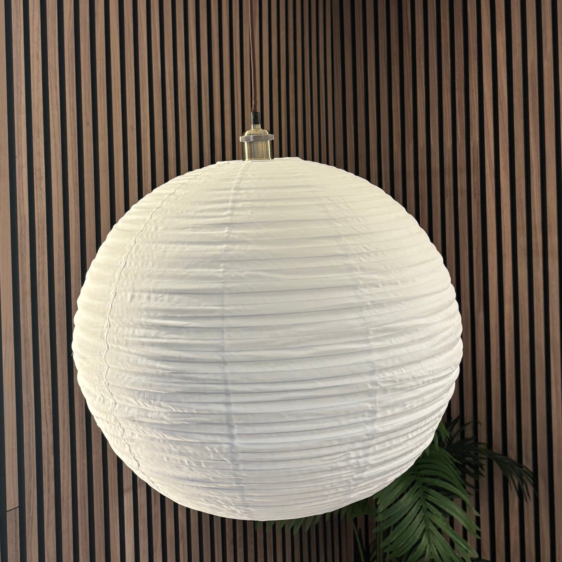 White spherical pendant light hanging against a striped wall.
