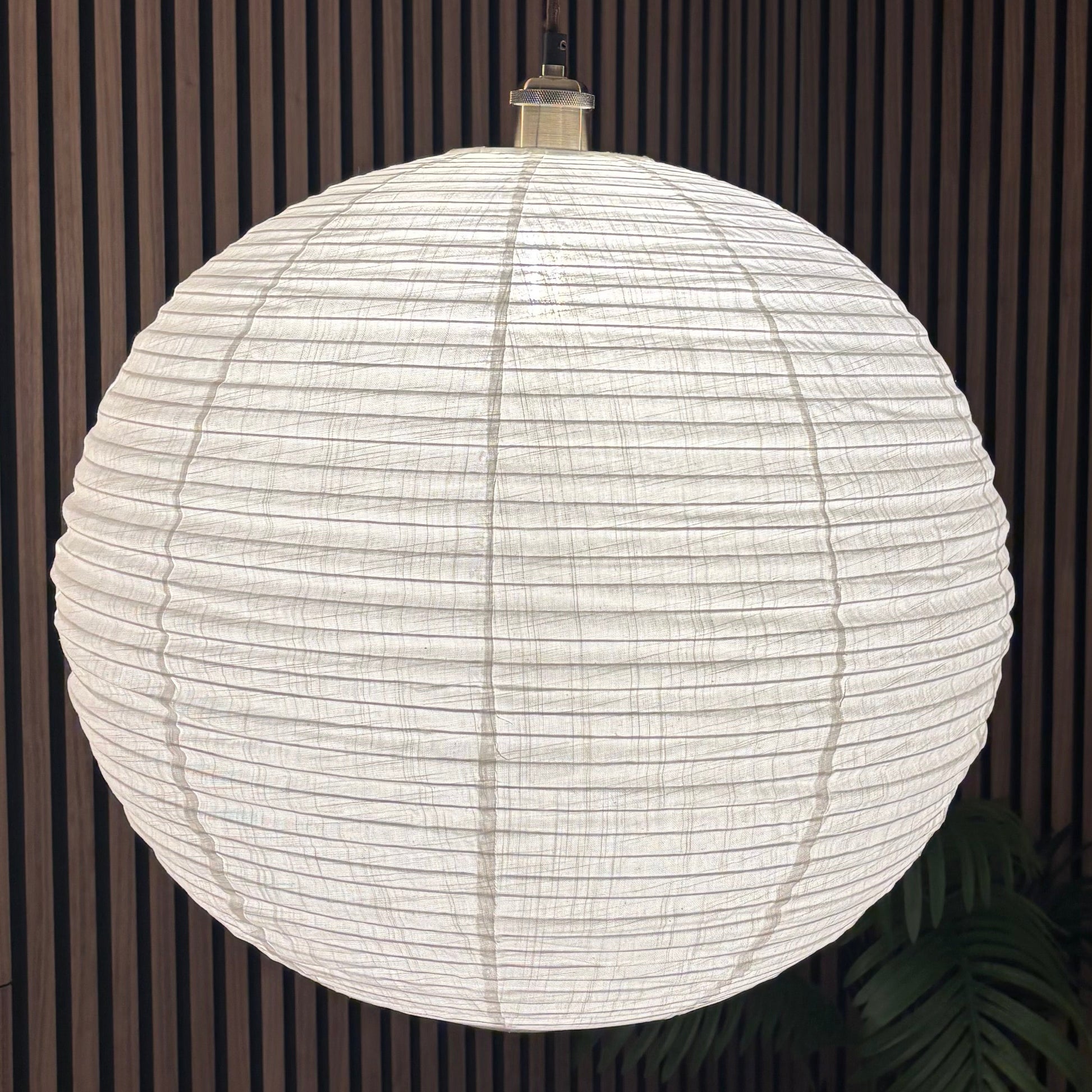 Spherical white pendant light hanging against a striped wall.
