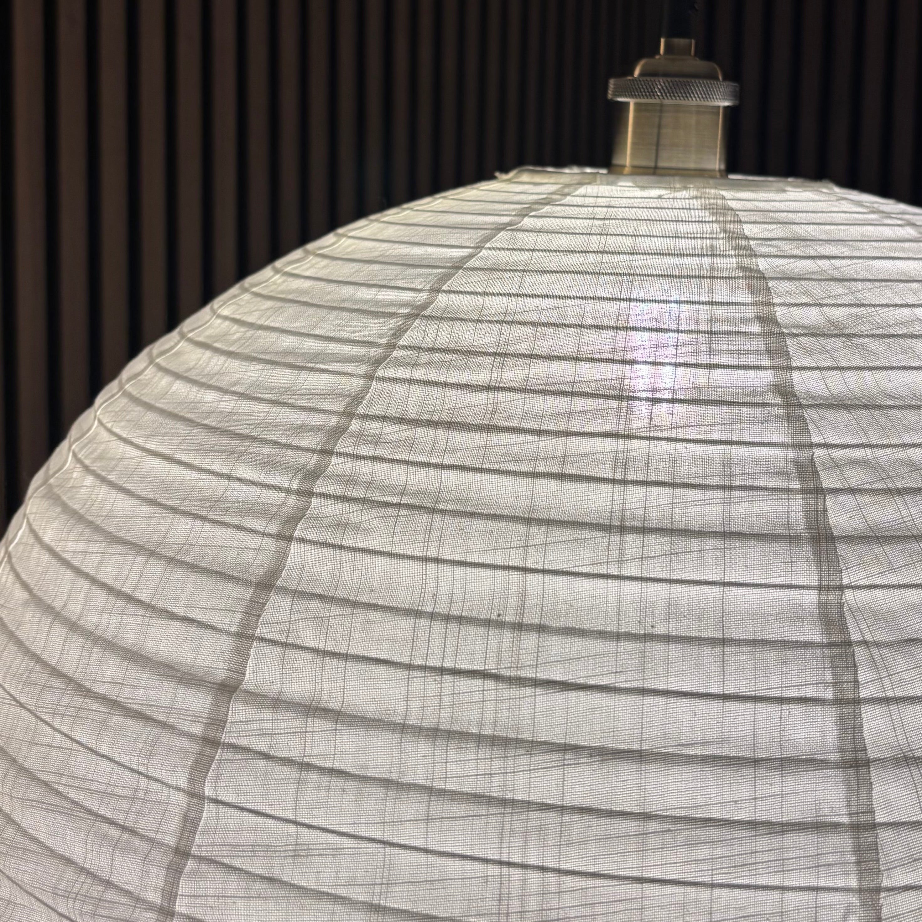 Close-up of a spherical lamp with woven design against a dark background