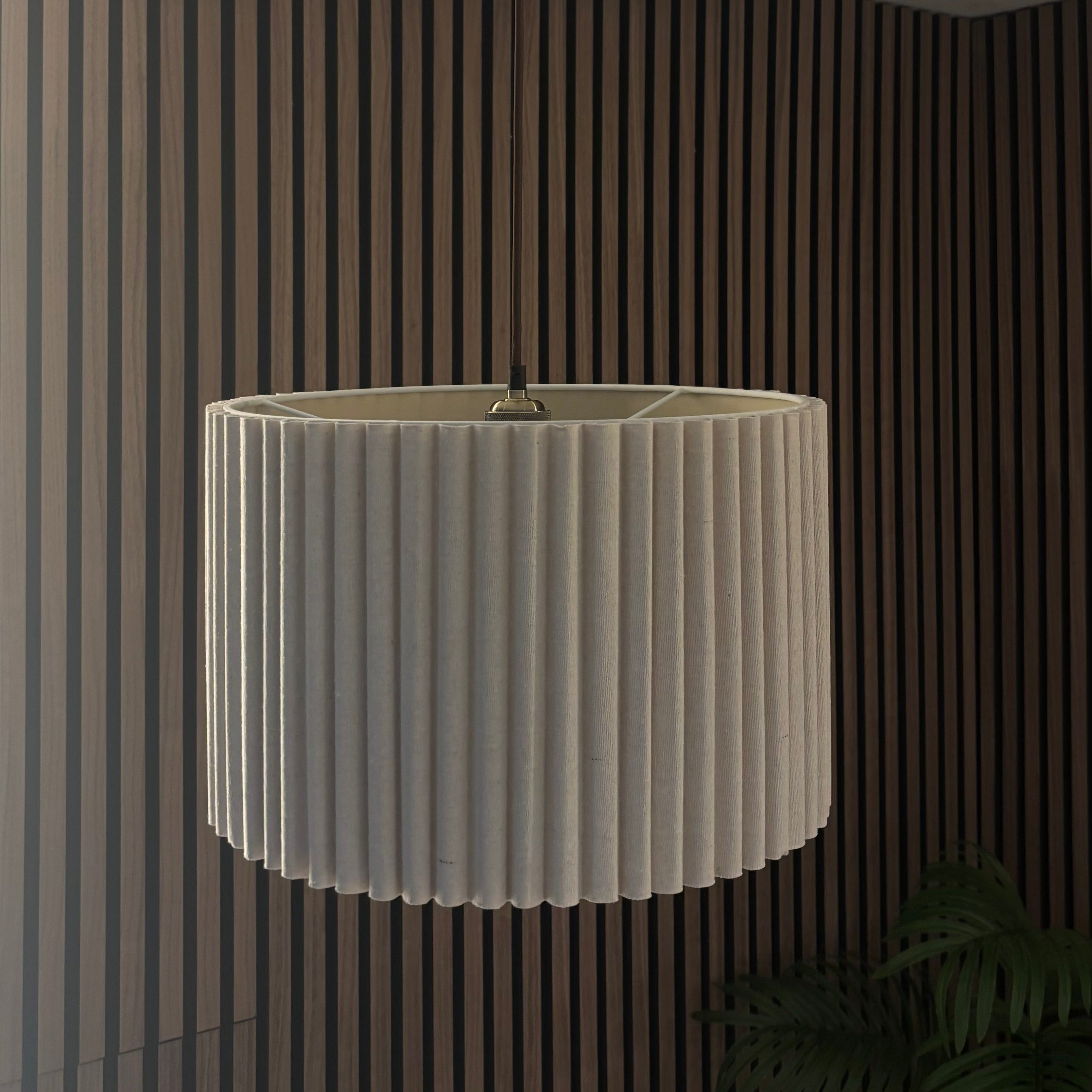 White pleated lampshade hanging from a ceiling in a room with striped walls.