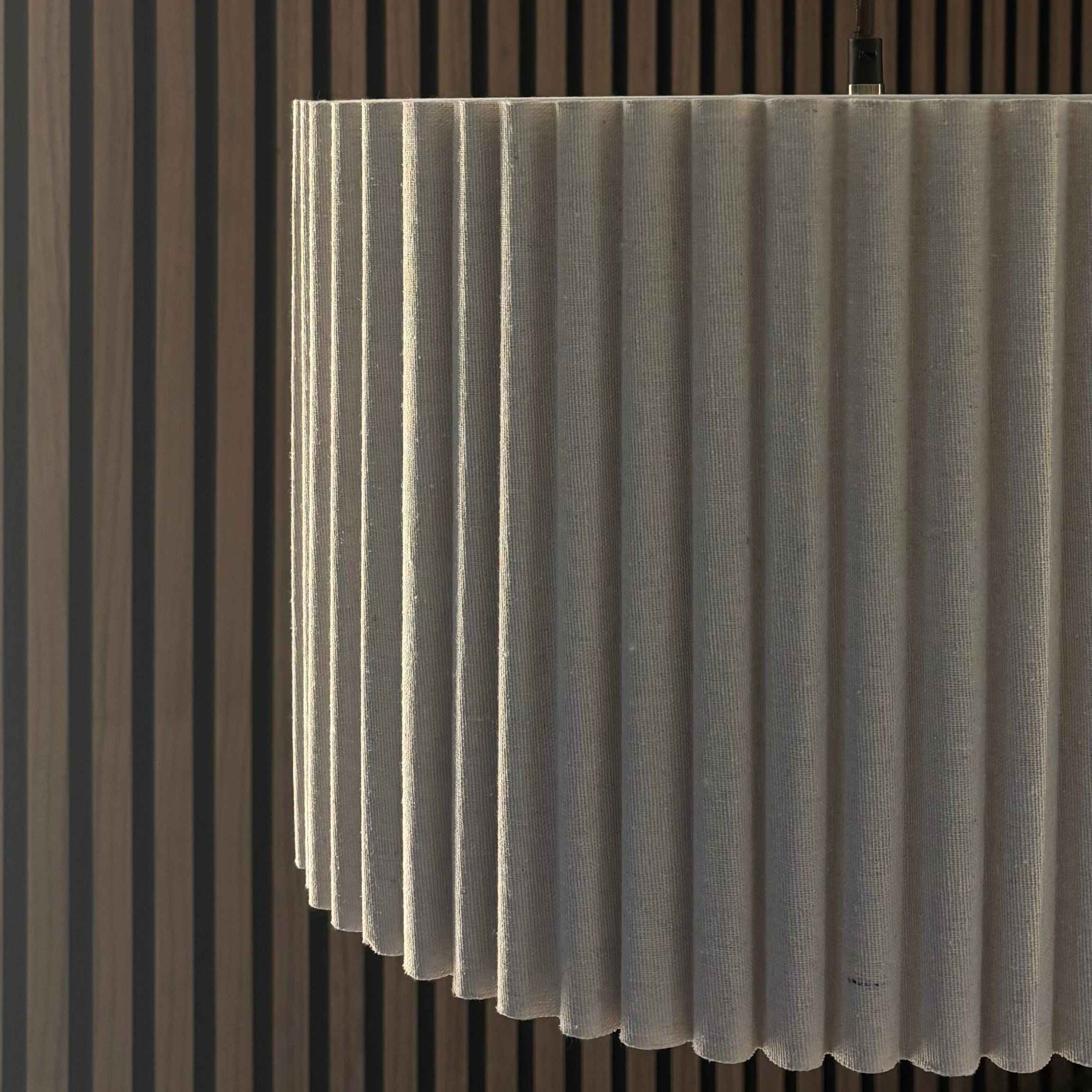 Modern pendant light fixture hanging from a ceiling with a striped wall in the background