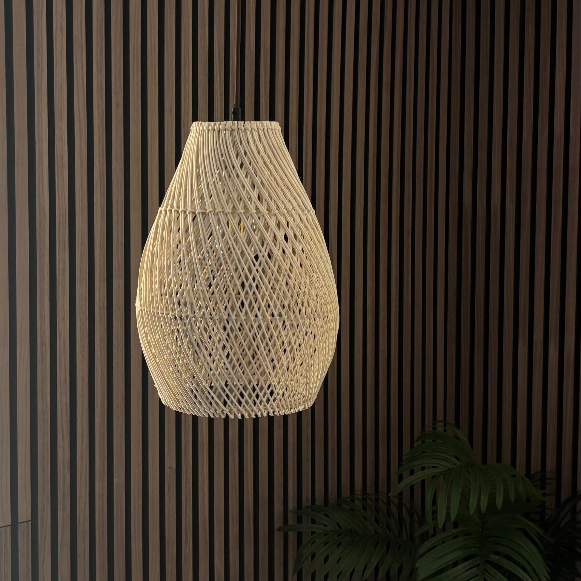 Modern pendant light hanging in a room with striped walls and a plant.