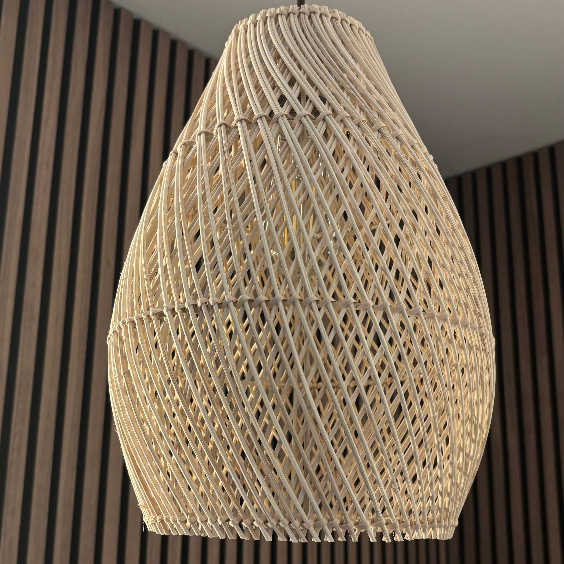 Woven pendant light hanging against a striped wall