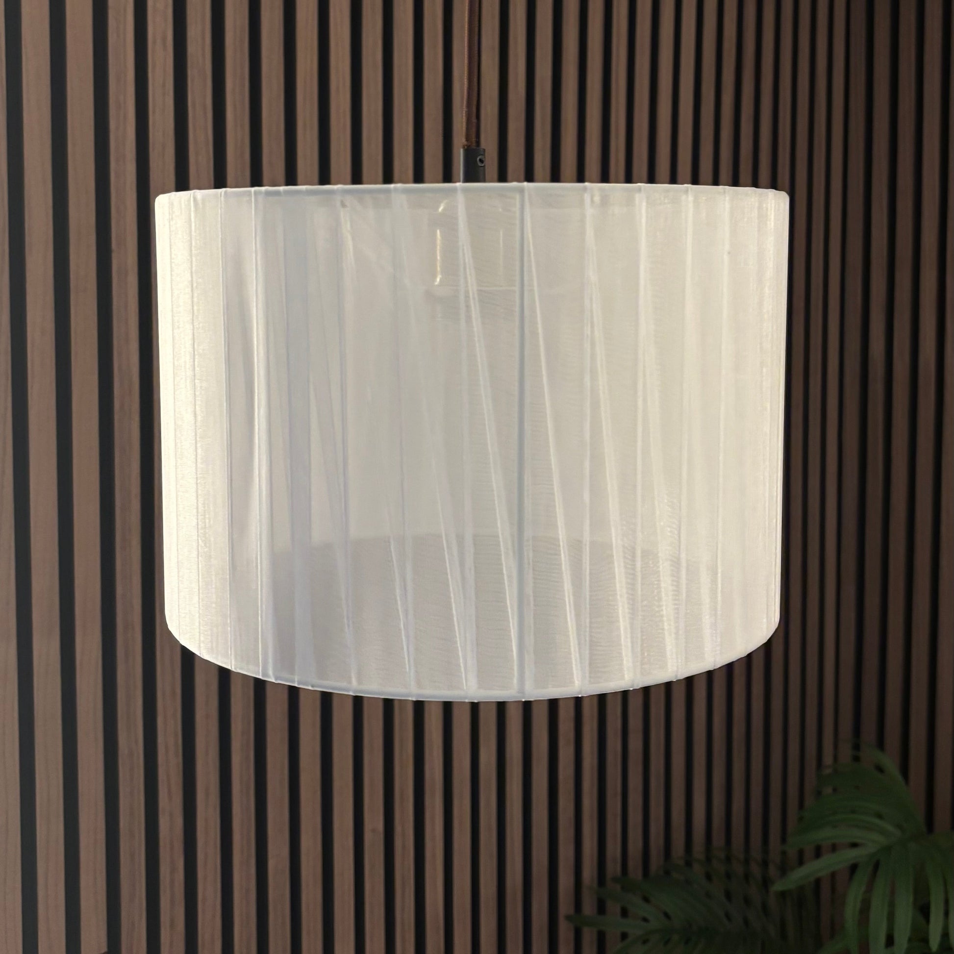 White cylindrical lampshade against a striped wall.