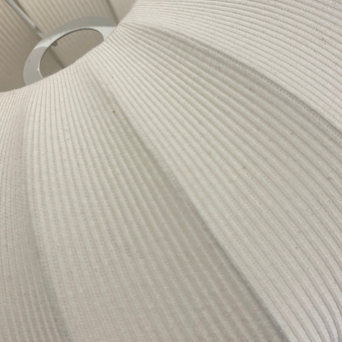 A close-up of a pleated fabric lampshade in a warm off-white or cream color, showing its ribbed texture and flared shape.