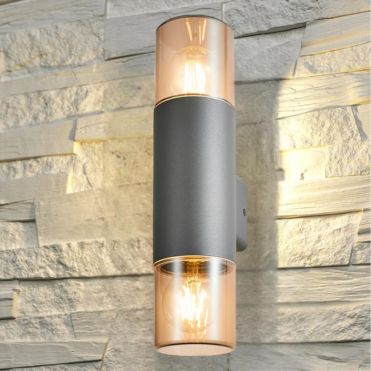 Our Cortez wall light looks great in modern settings. This wall light has a modern round tube design with anthracite finish aluminium body and 2 polycarbonate smoked diffusers. This wall light is perfect for any outdoor space requiring light and security such as gardens, driveways, doorways workspaces, pubs and hotels.