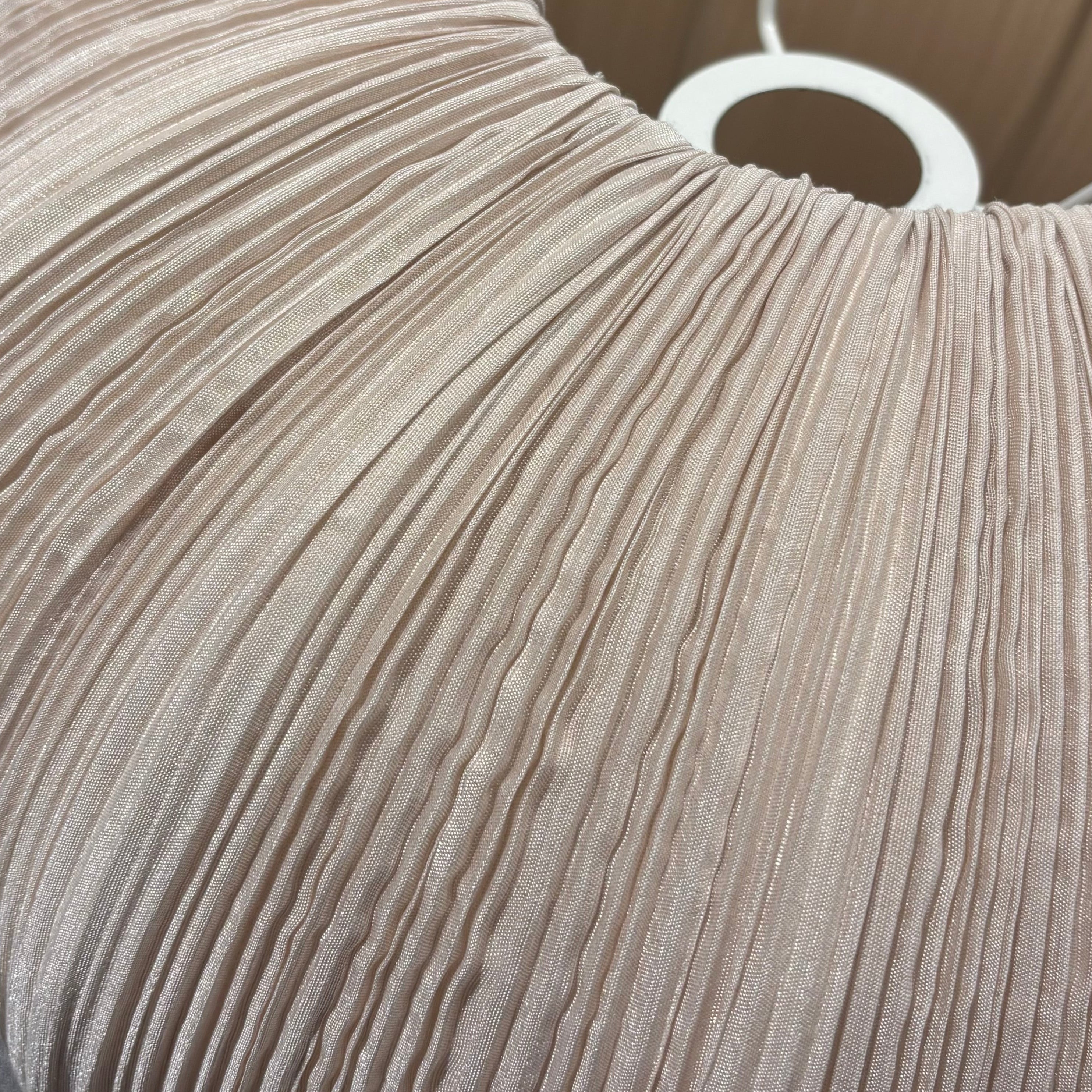 Close-up of a pleated beige lampshade on a gray surface.