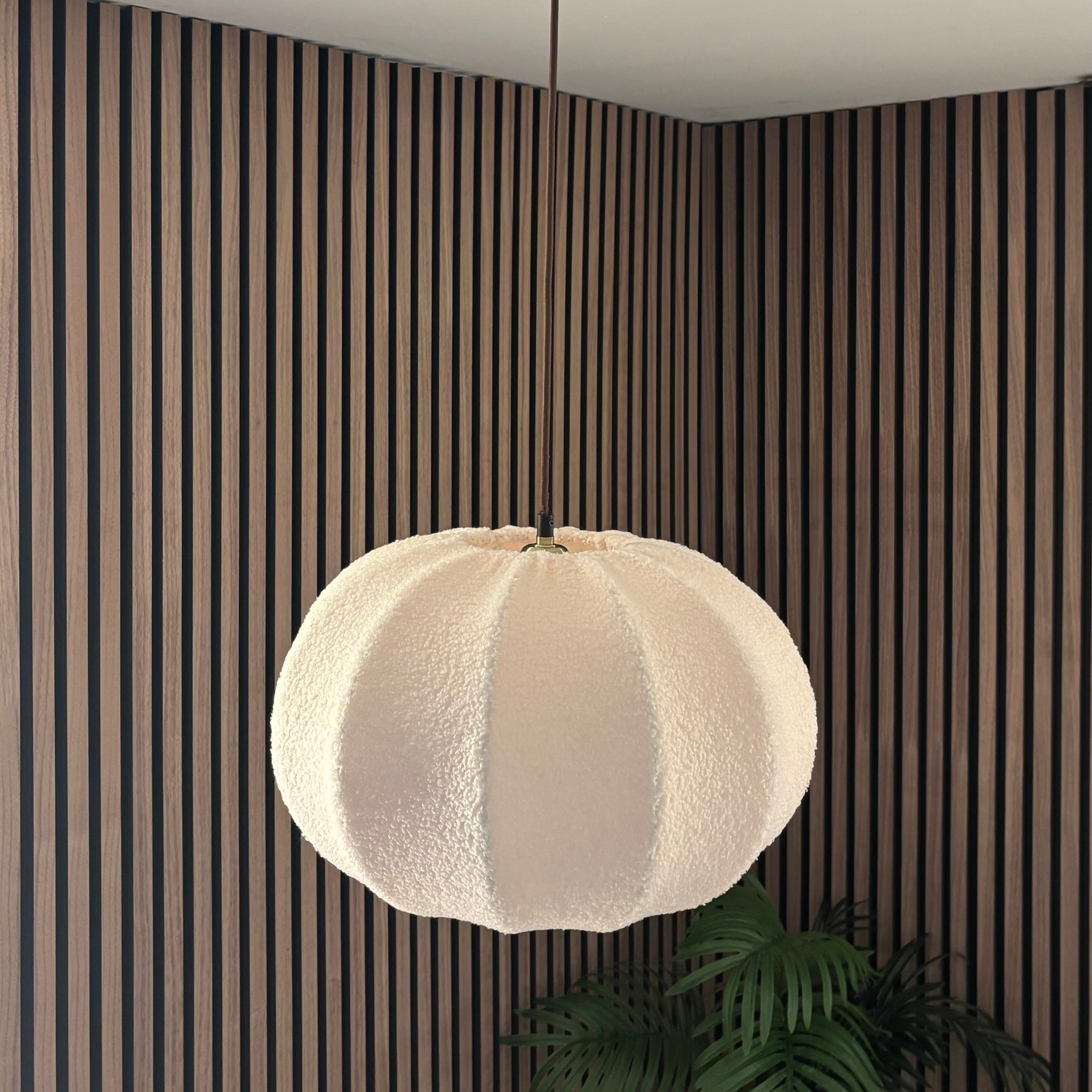 White pendant light hanging from a ceiling in a room with striped walls.
