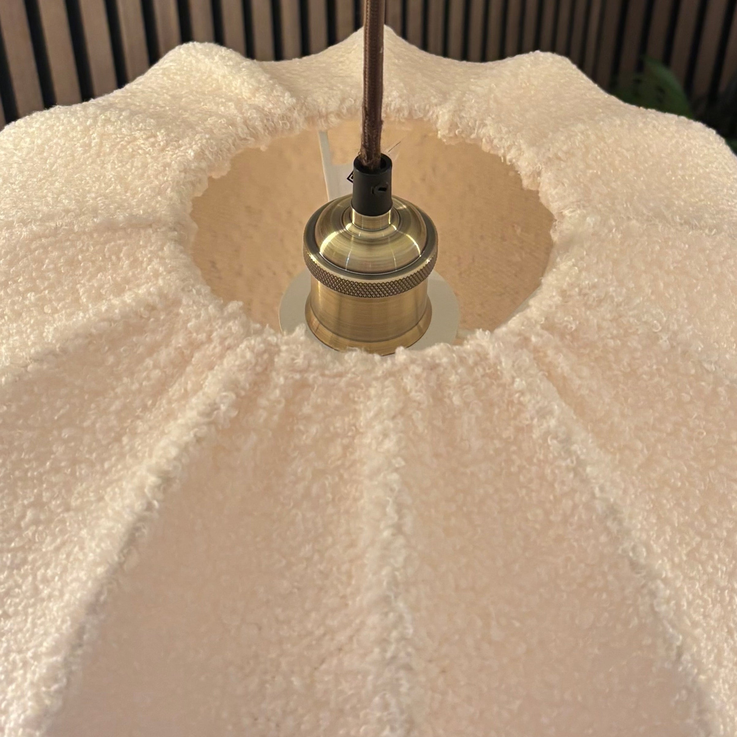 Close-up of a light fixture with a white lampshade against a striped background