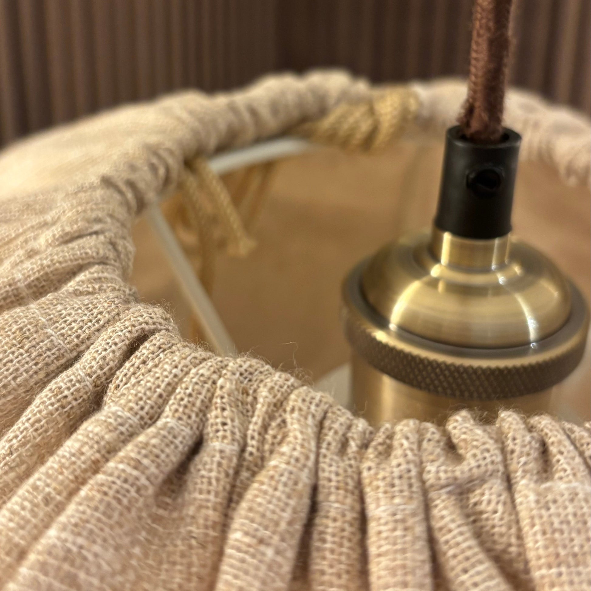 Close-up of a textured lampshade with a visible light bulb and fixture.