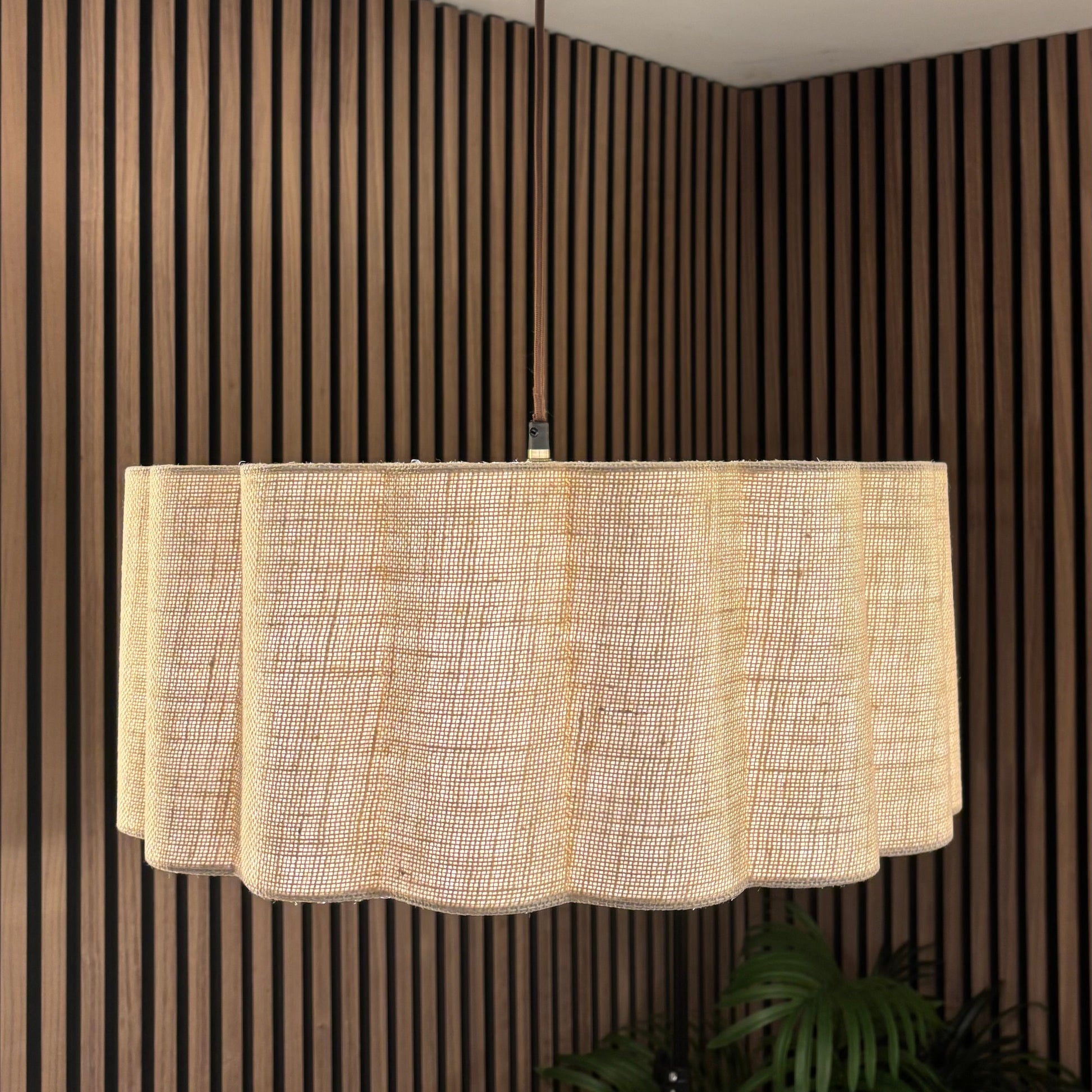 Ceiling light fixture with a textured lampshade against a striped wall.