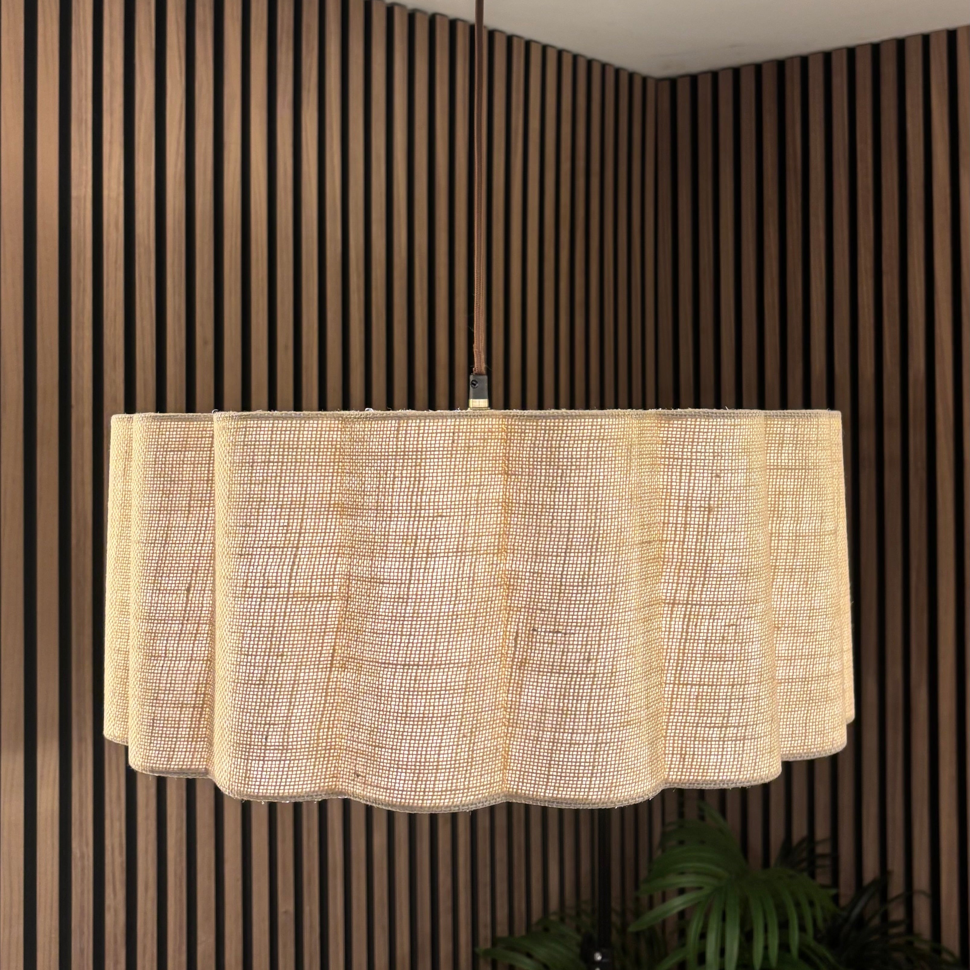 Ceiling light fixture with a textured lampshade against a striped wall.