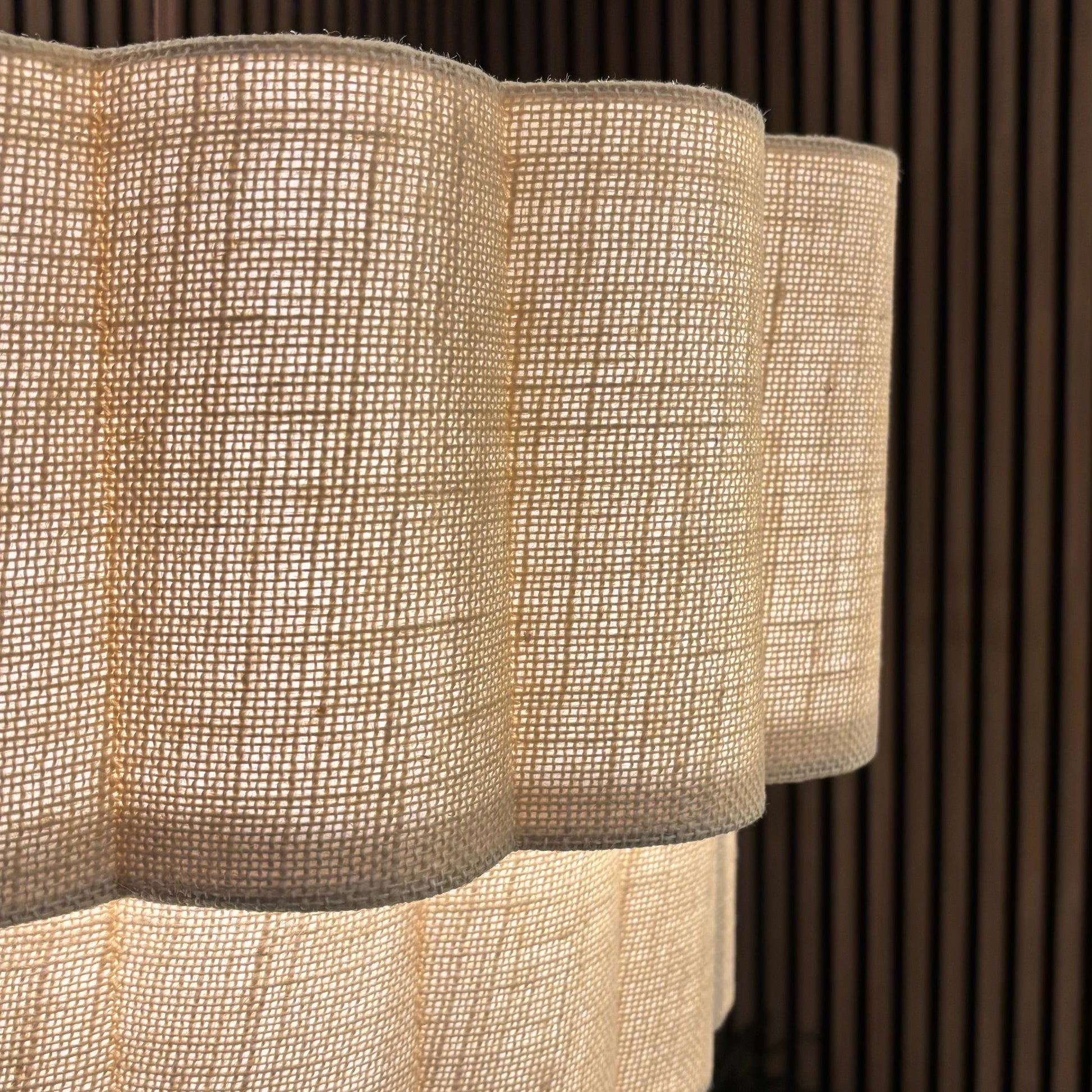 Textured pendant light fixture with a scalloped edge against a wooden panel background