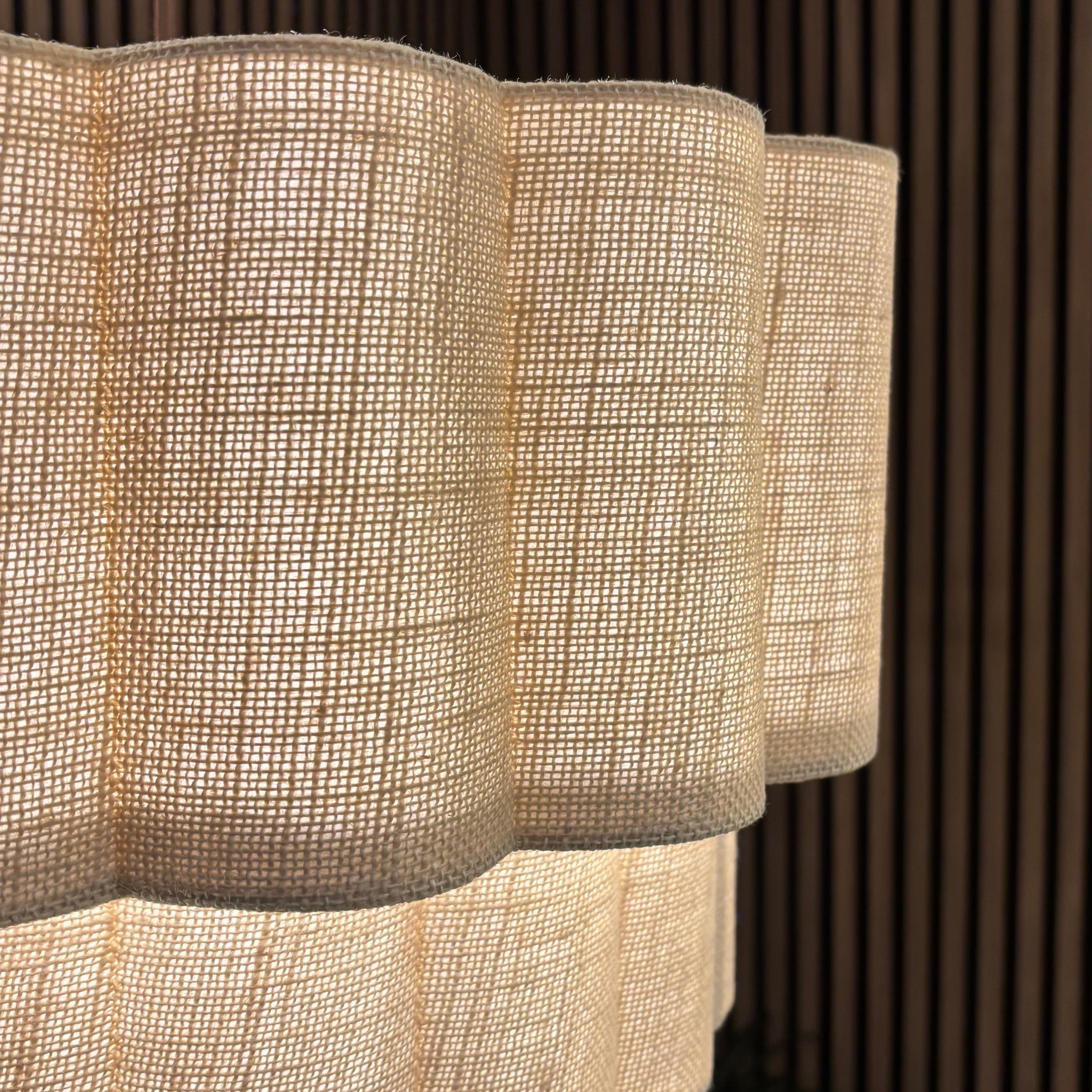 Textured pendant light fixture with a scalloped edge against a wooden panel background