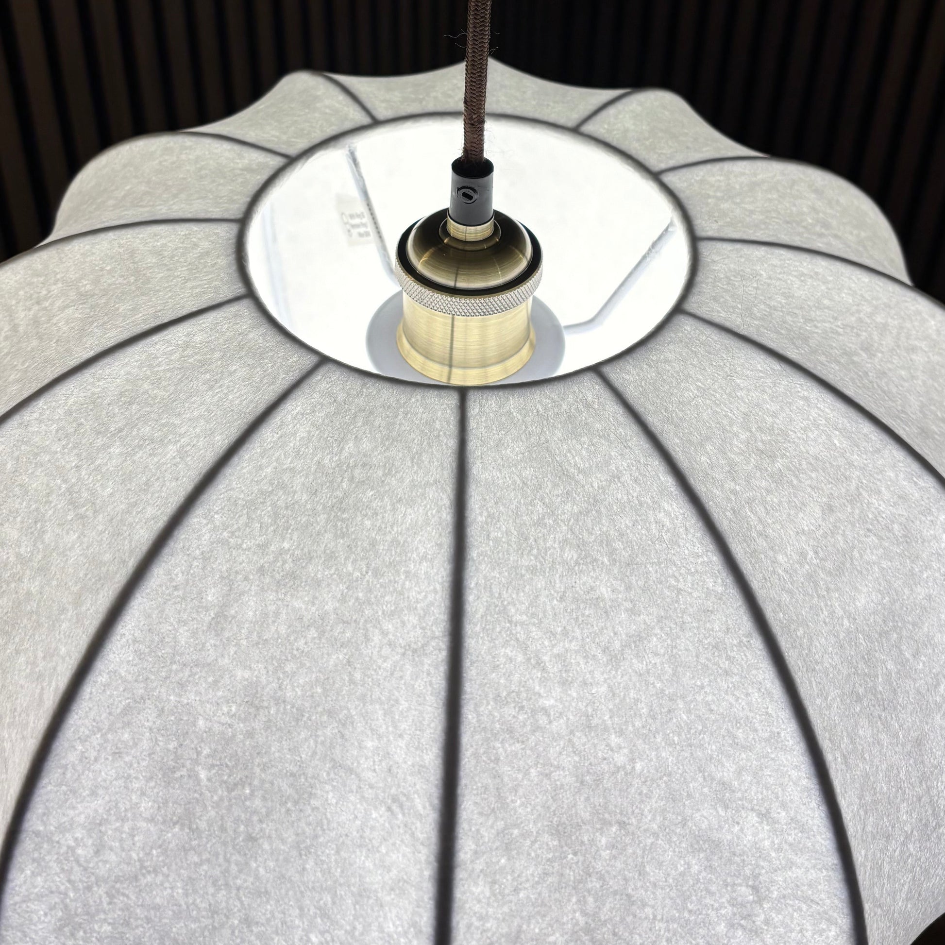 Close-up of a lampshade with a metallic fixture against a dark background