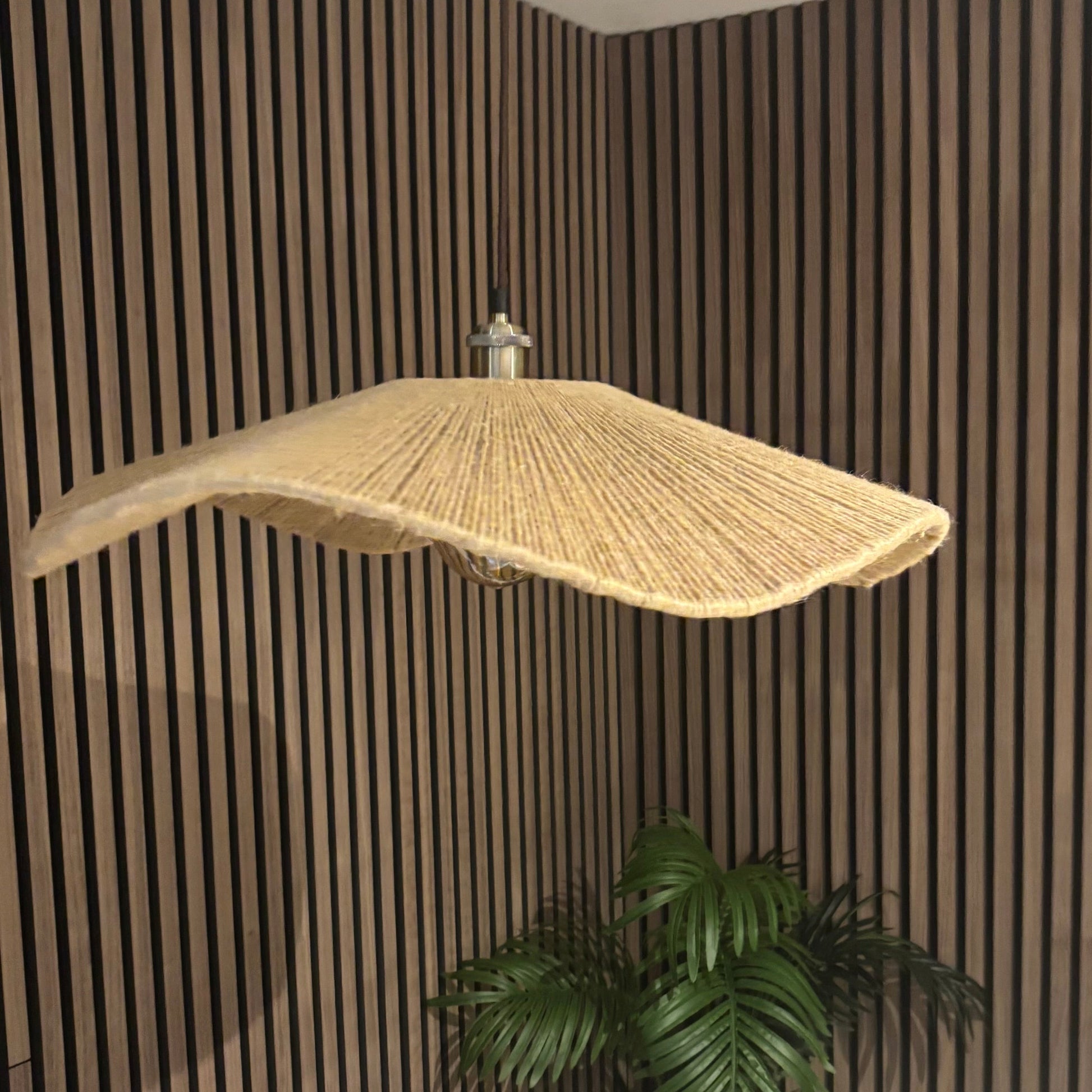 Ceiling light fixture with a wicker shade in a room with striped walls and a plant.