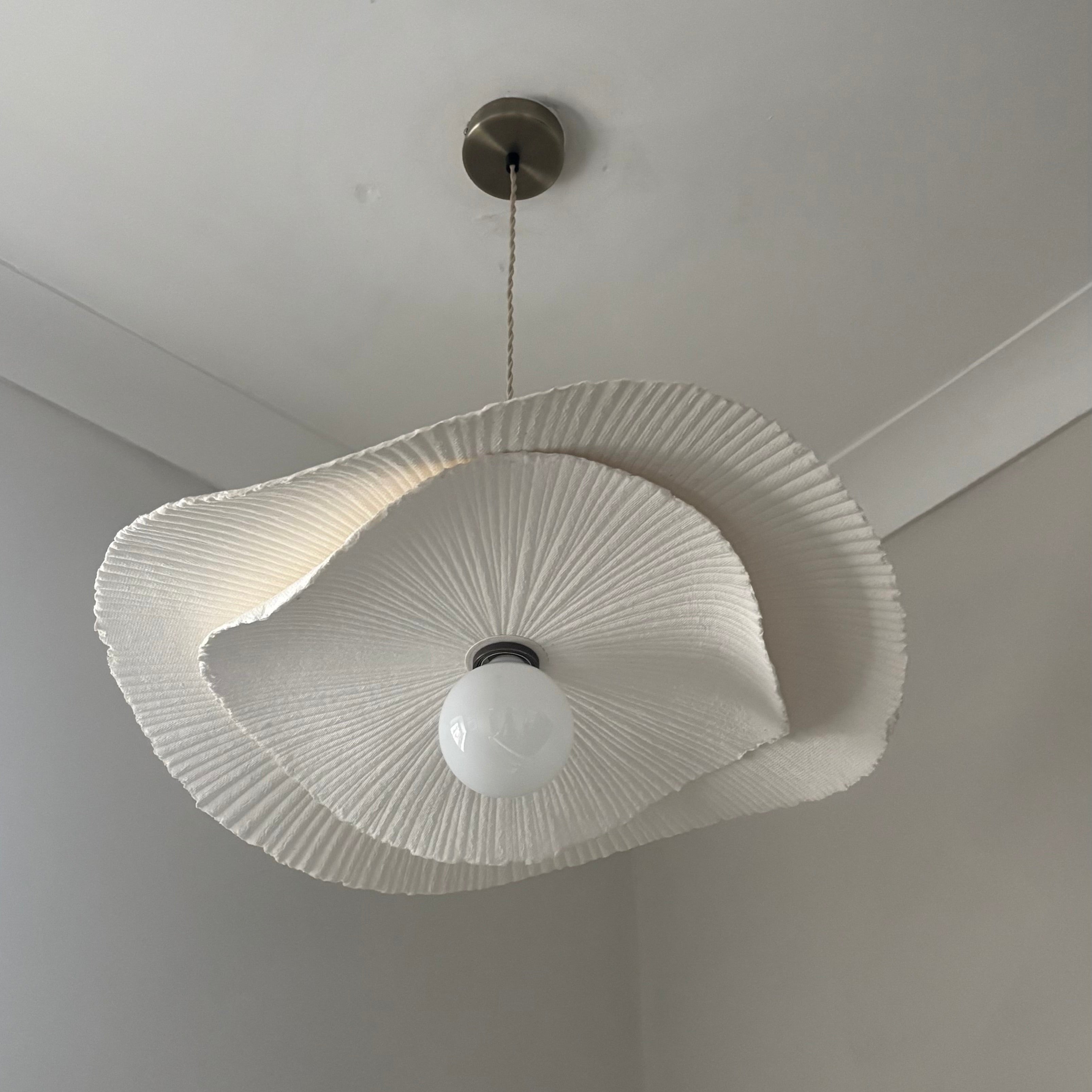 Ceiling light fixture with white lampshade on a plain ceiling