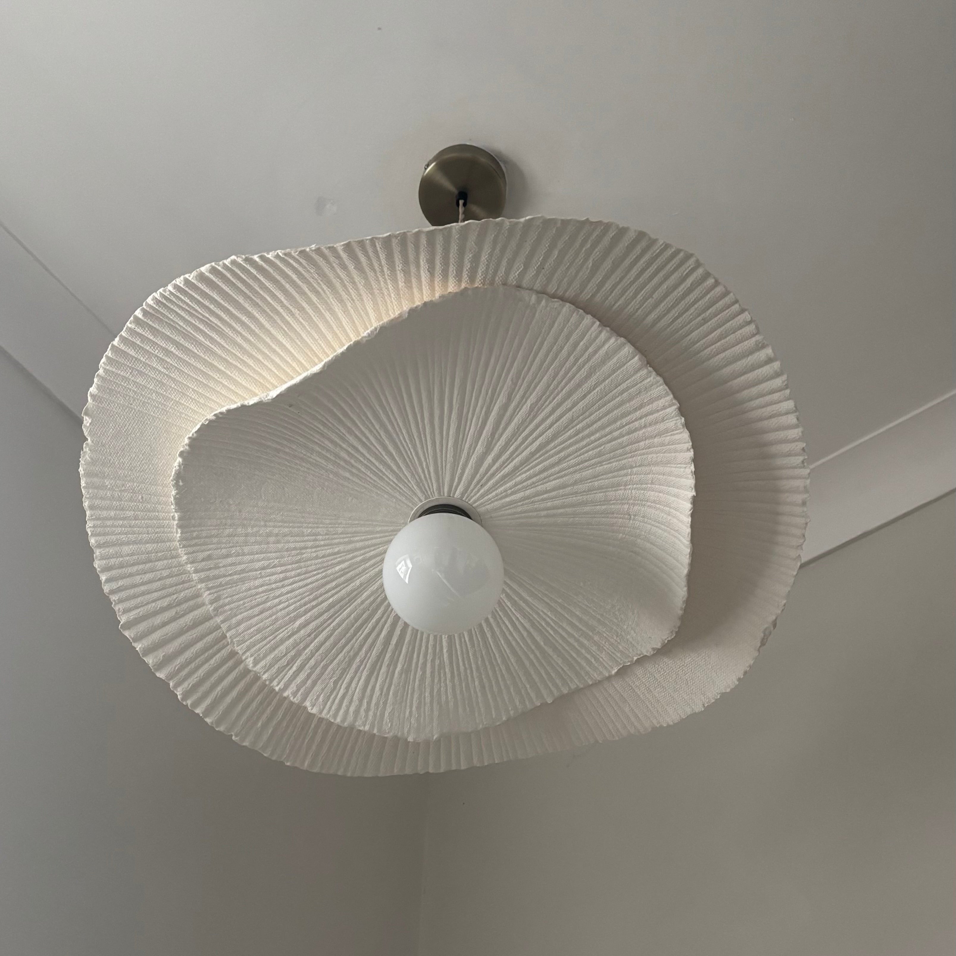 Ceiling light fixture with white lampshade on a plain ceiling
