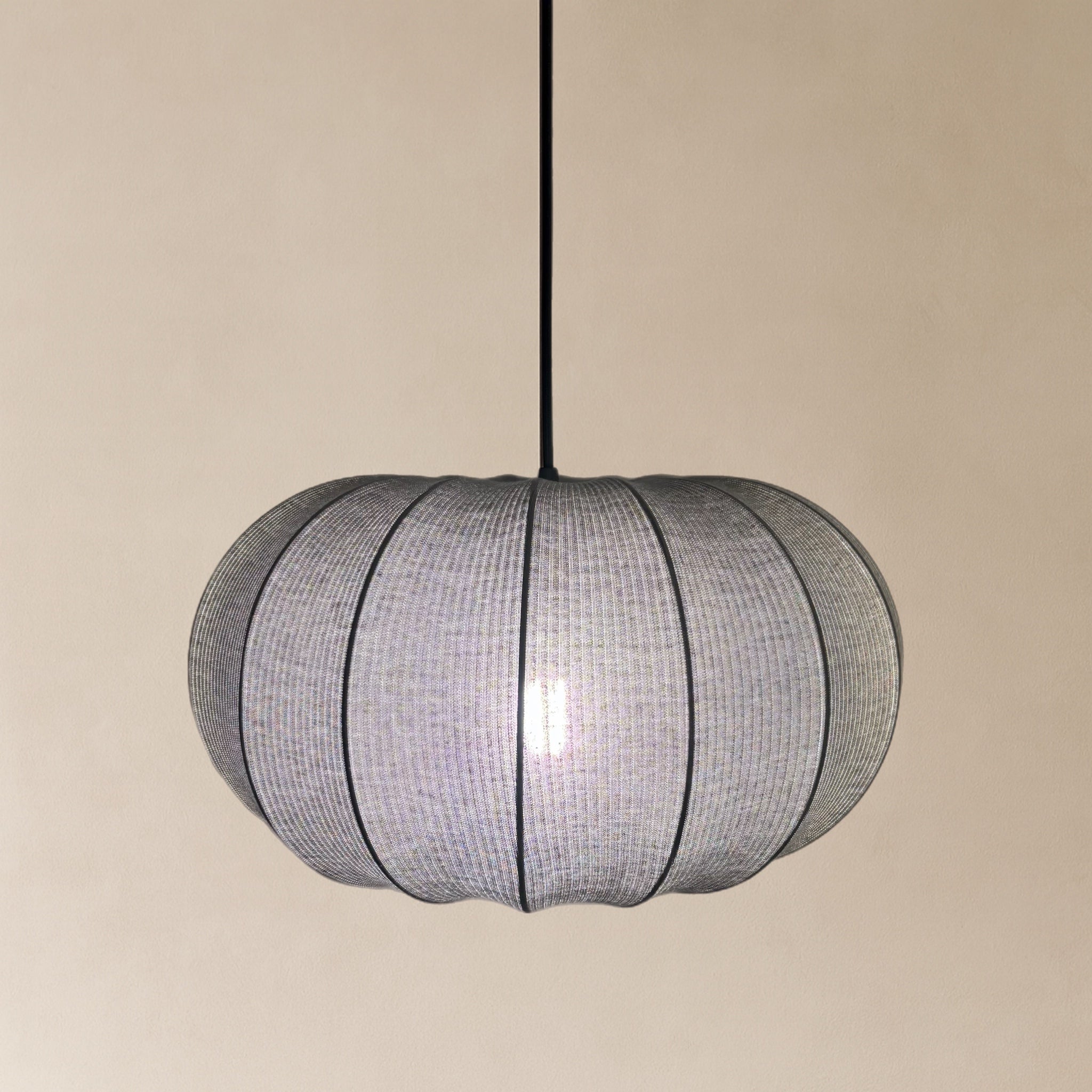 Spherical pendant light with mesh design on a beige background