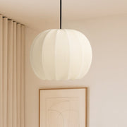 Modern bedroom interior with a pendant light, wall art, and a plant.
