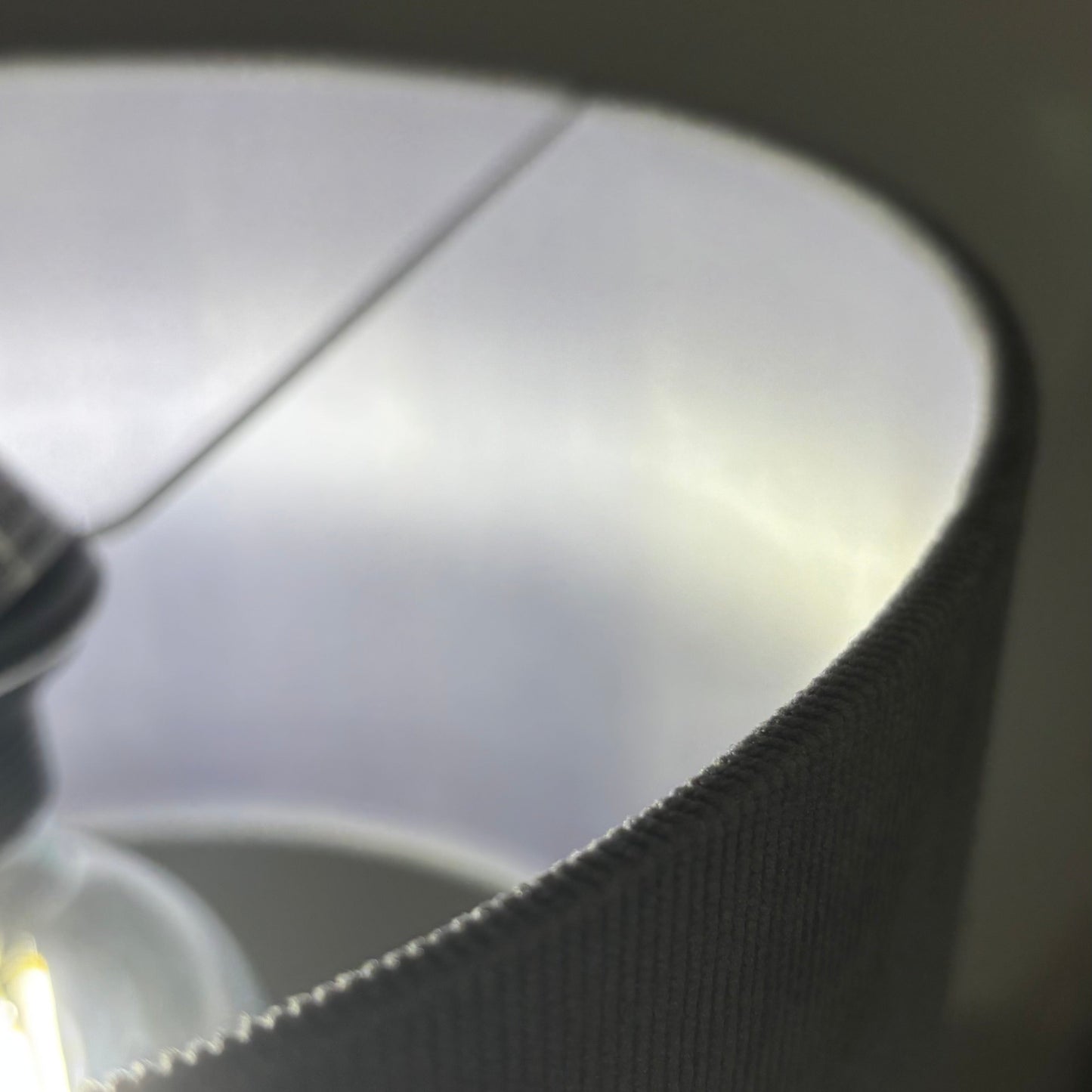 Close-up of a light bulb inside a lampshade with a dark background