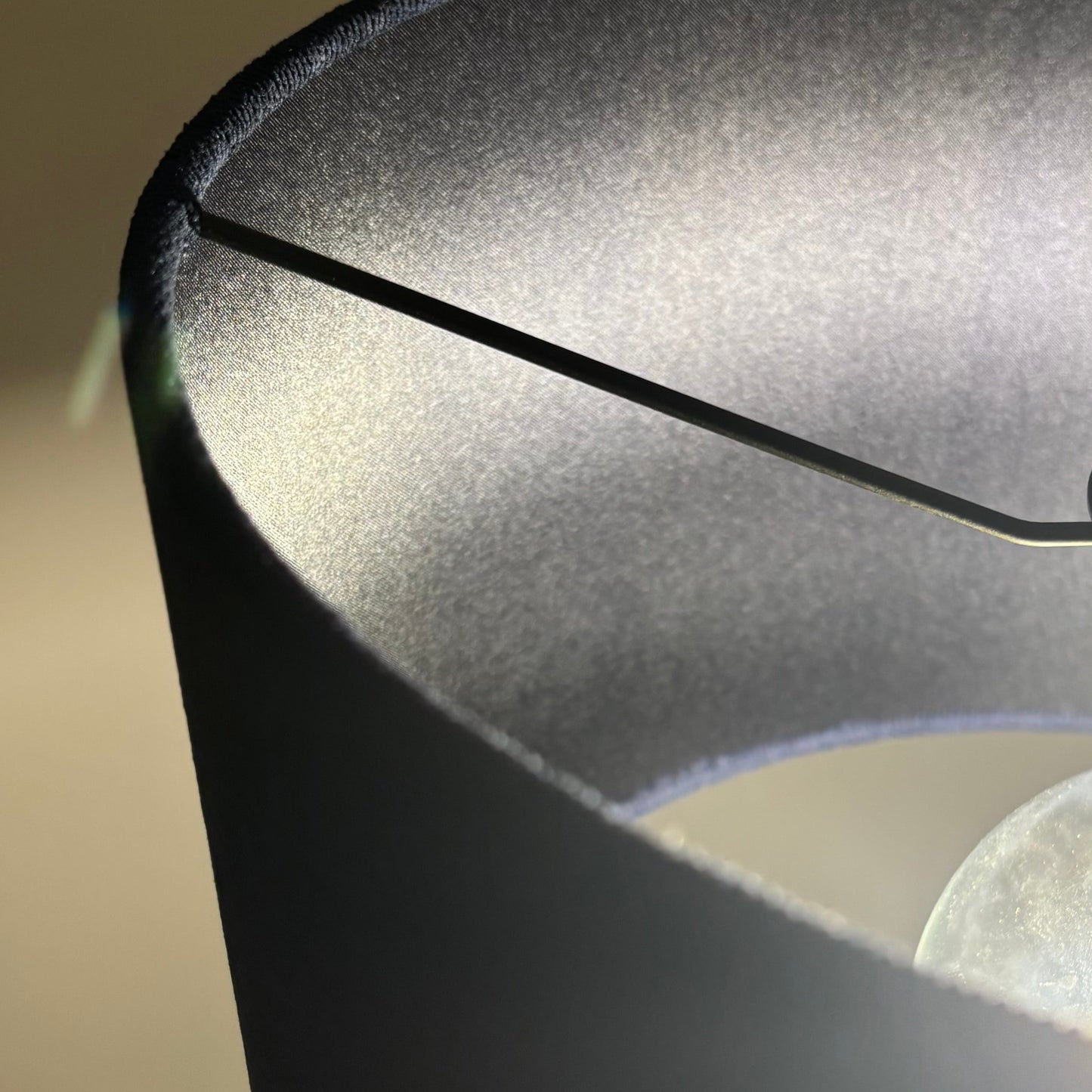 Close-up of a lamp with a navy shade and visible bulb.