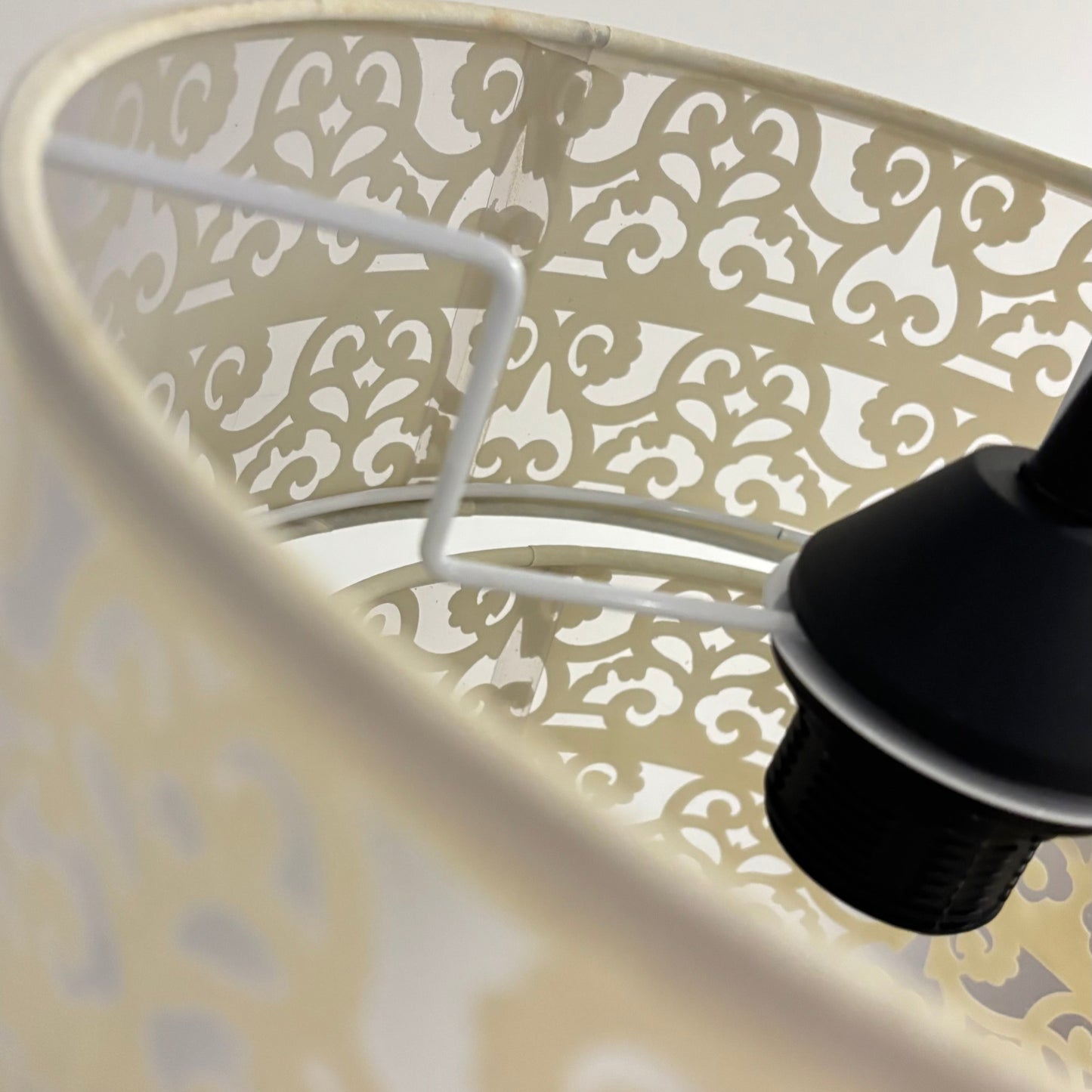 Decorative lampshade with intricate patterns and a black base on a light background