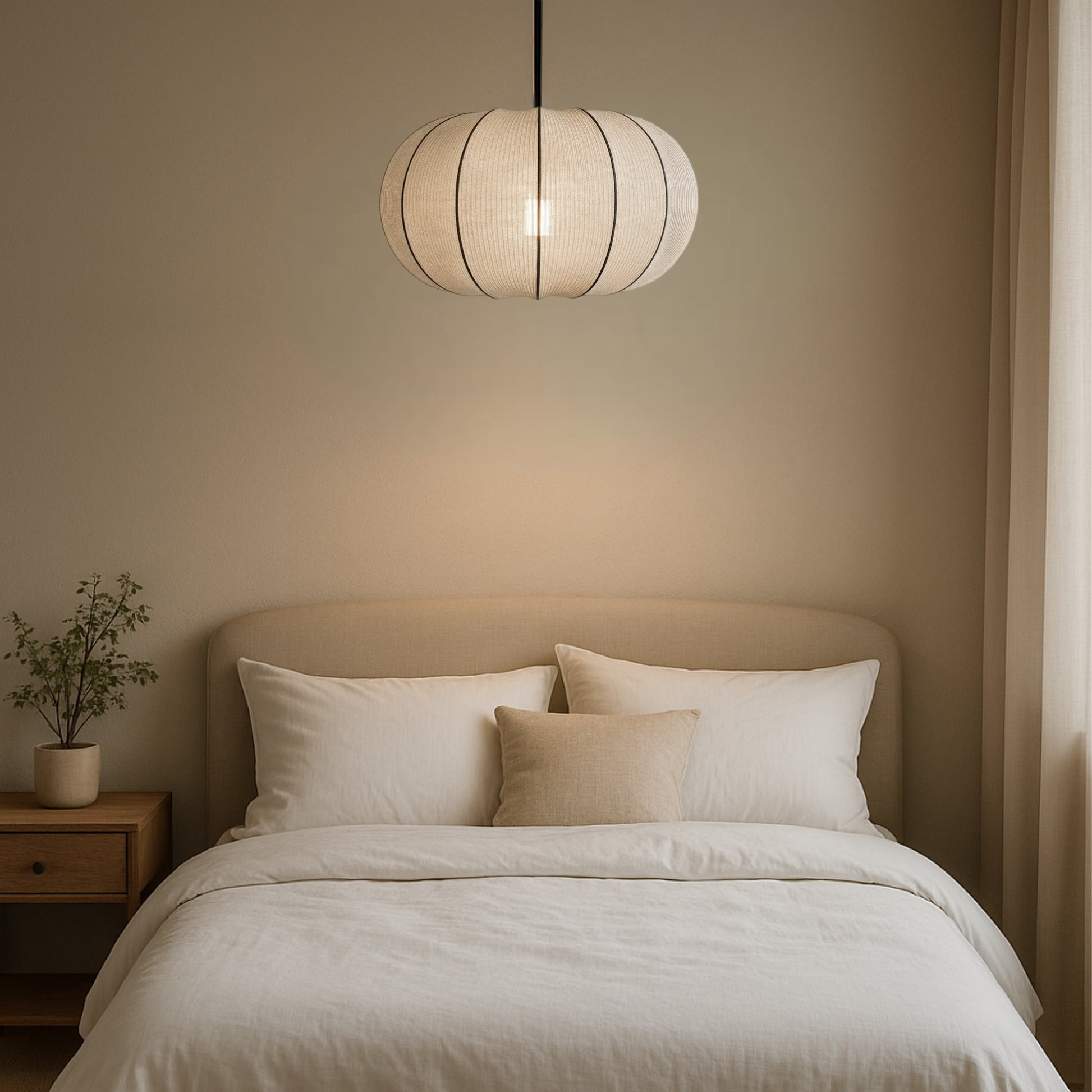 Neatly made bed with pillows under a pendant light in a softly lit room.