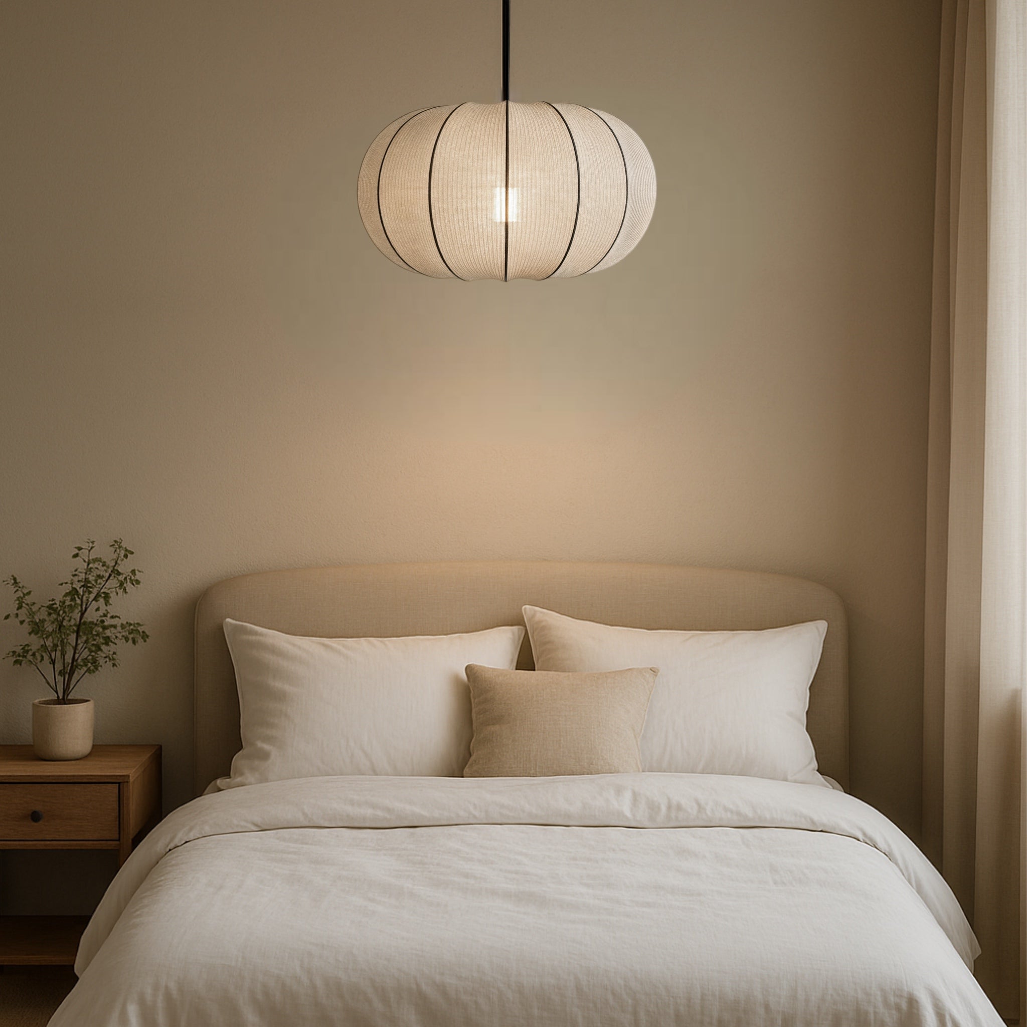 Neatly made bed with pillows under a pendant light in a softly lit room.