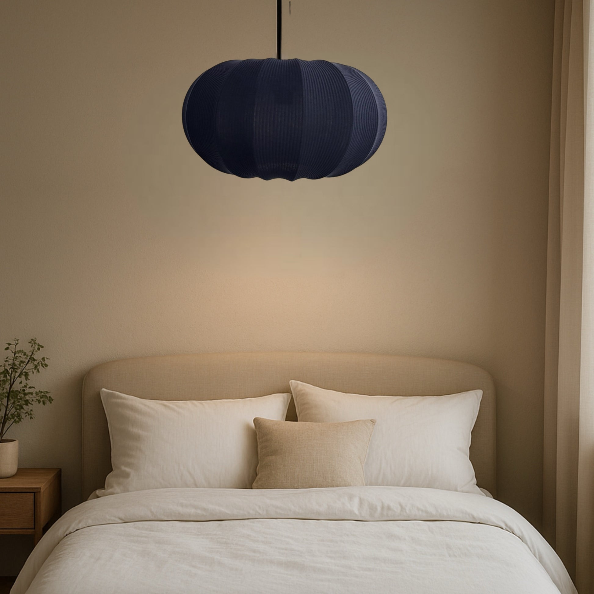 Navy blue pendant light above a bed with beige headboard and white bedding.