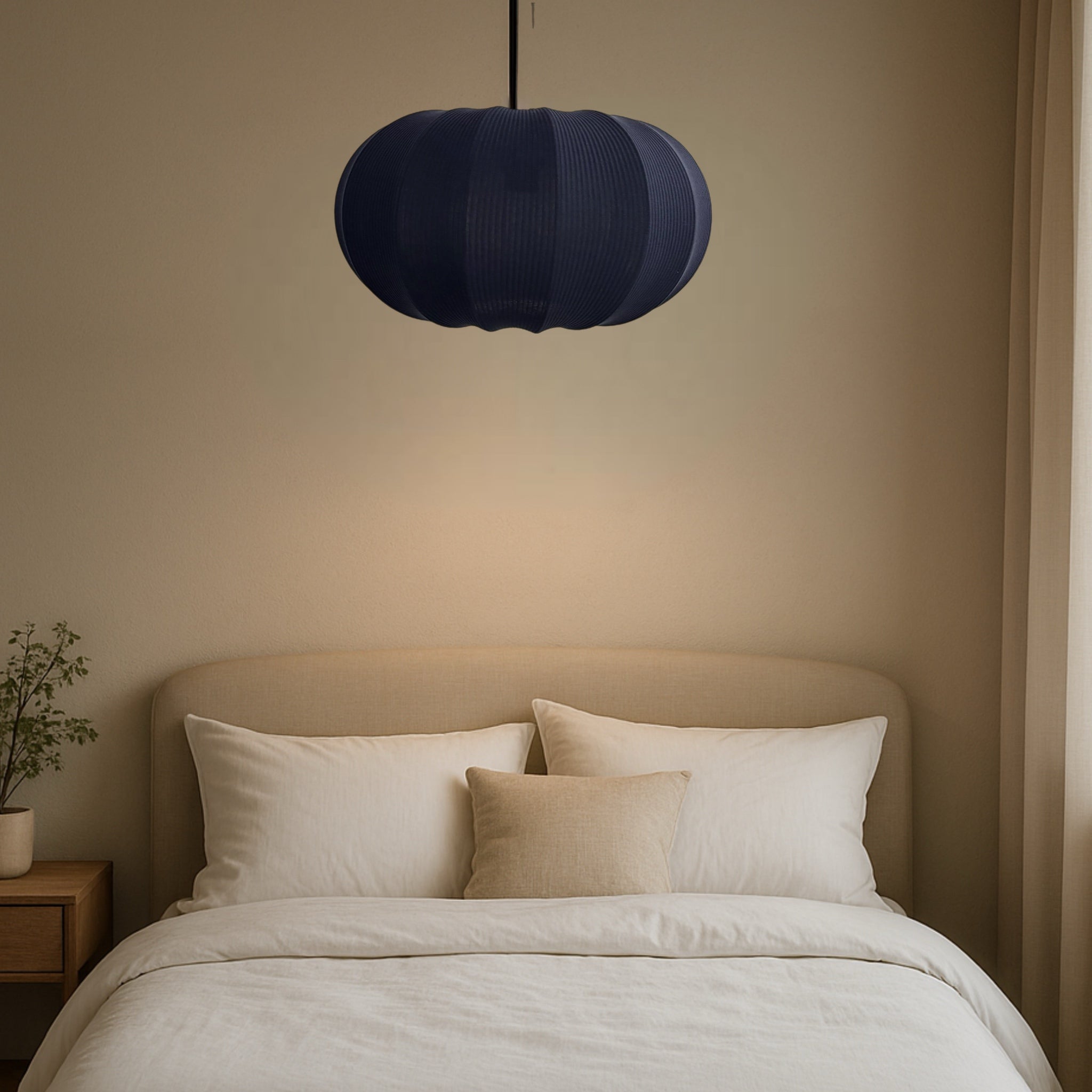 Navy blue pendant light above a bed with beige headboard and white bedding.