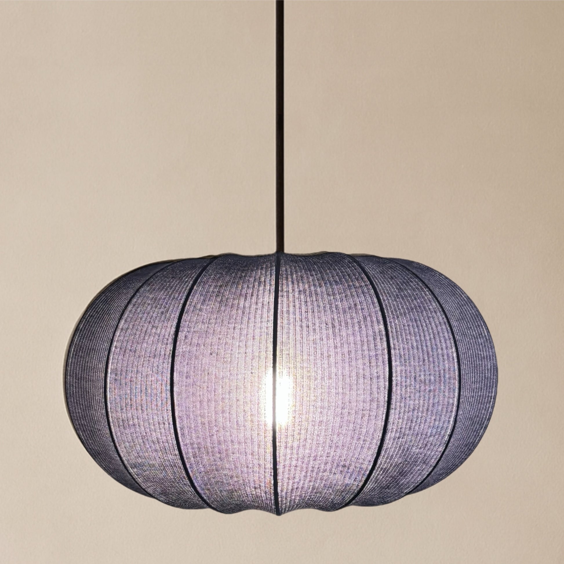 Spherical pendant light with woven design on a beige background