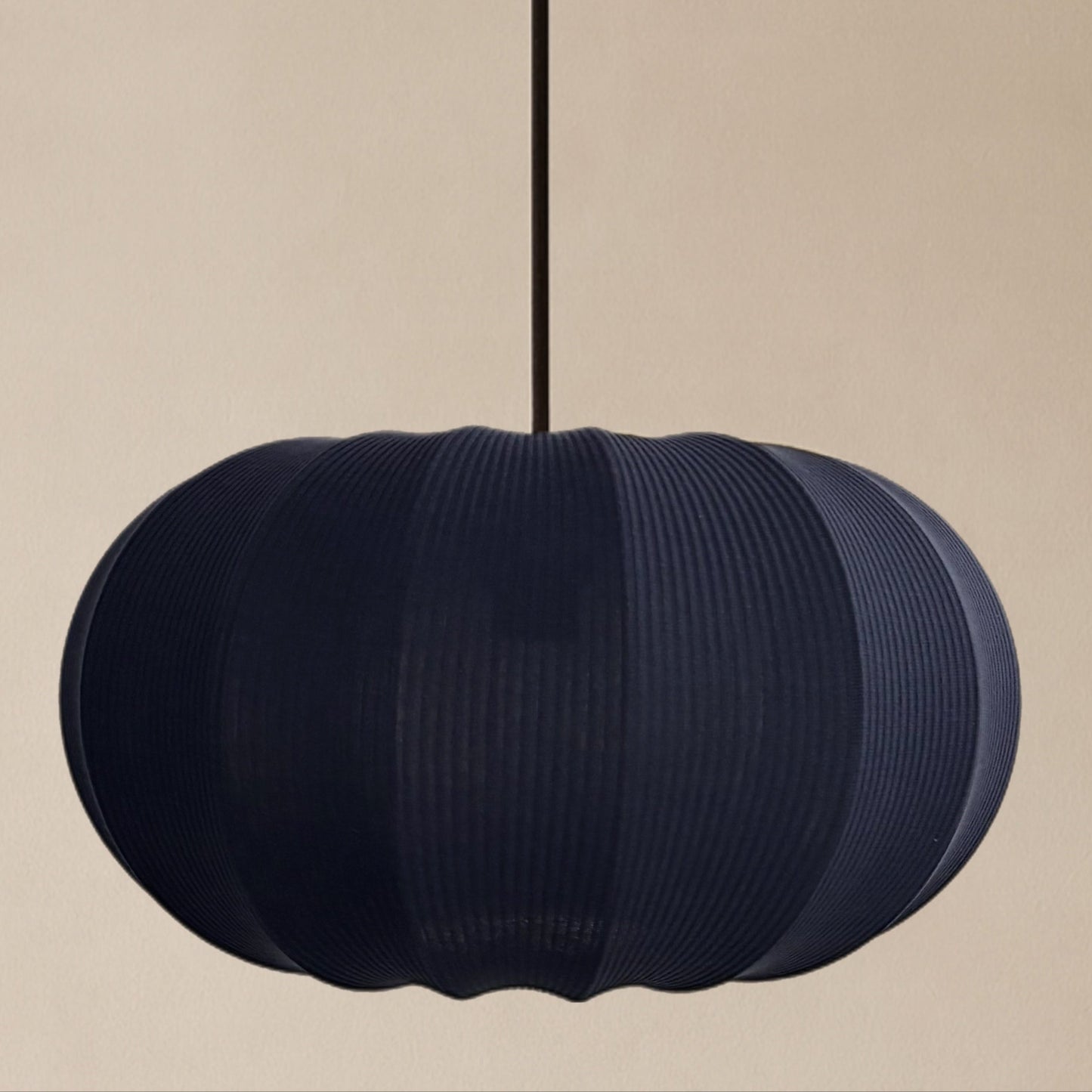 Navy ribbed pendant light on a beige background