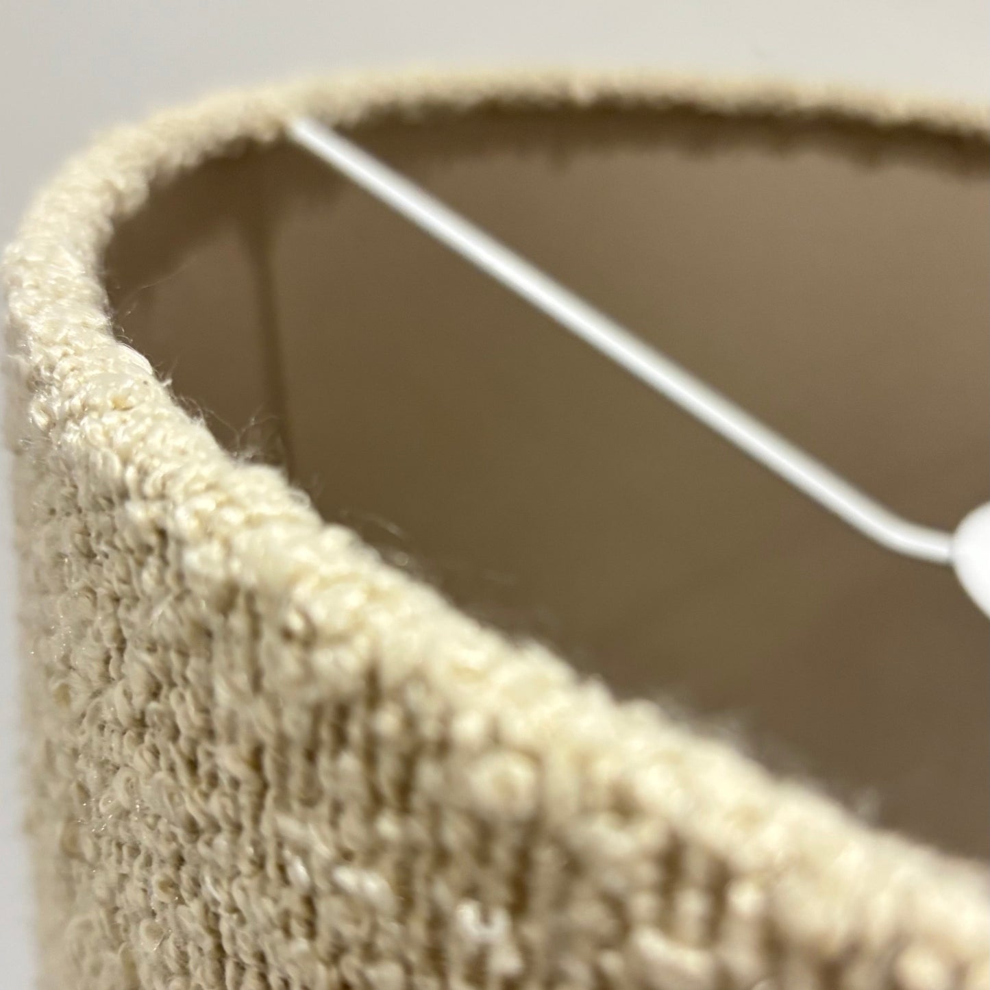 Close-up of a textured beige wall hook with a white string.