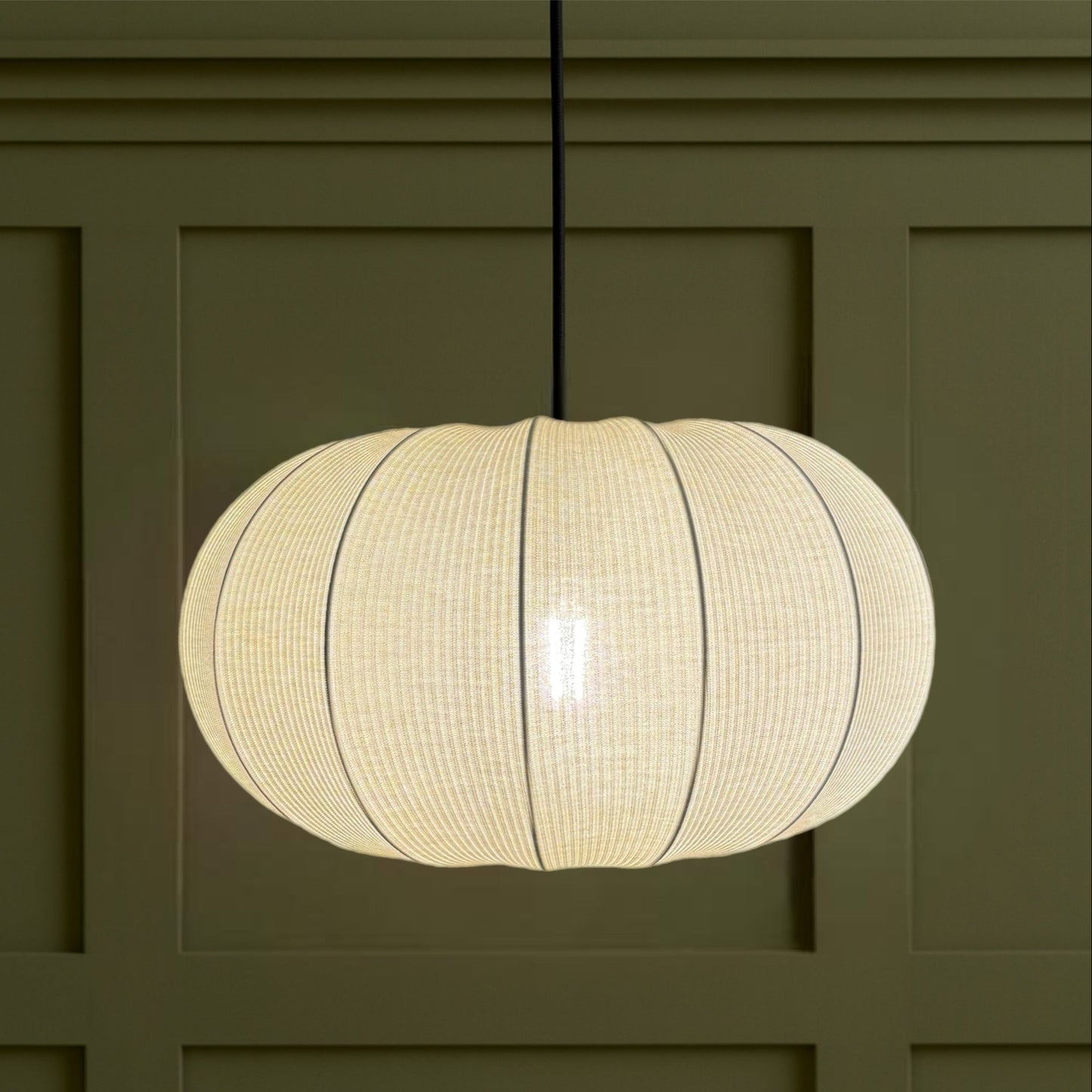 Round woven pendant light fixture on a green wall