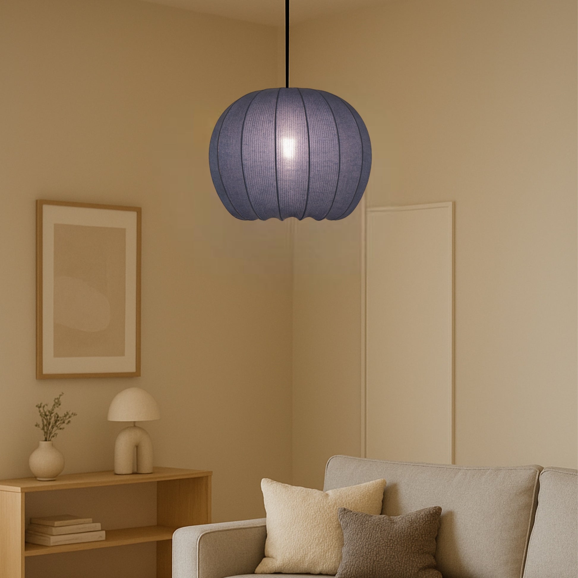 Blue pendant lamp hanging in a living room with beige walls and a sofa.