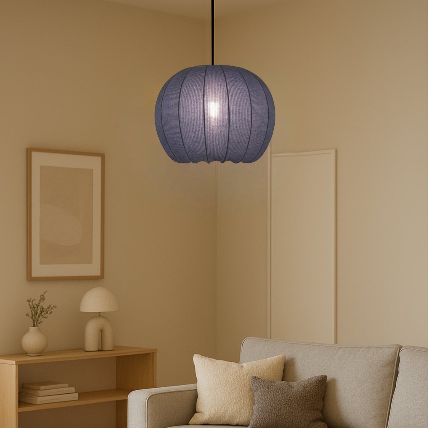 Blue pendant lamp hanging in a living room with beige walls and a sofa.