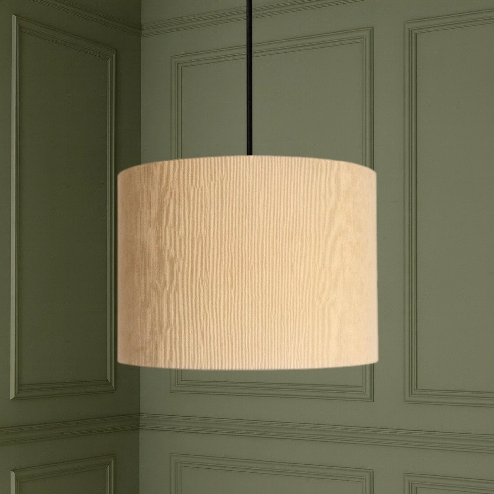 Beige pendant lamp hanging against a green paneled wall