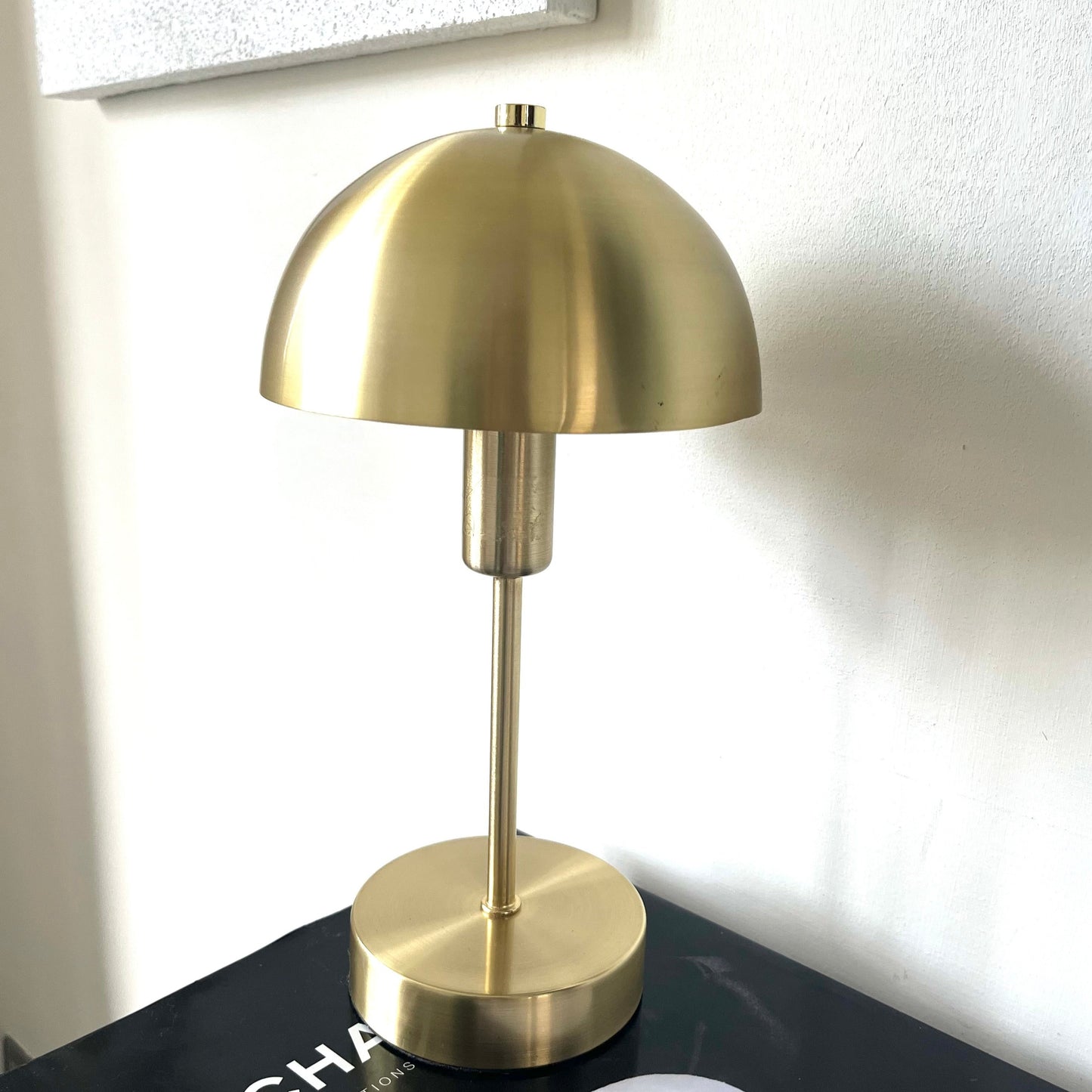 Introducing our Nellie table lamp with its distinctive dome-shaped shade and metal frame, this lamp will become a strong visual element in your space. Thanks to its gold matt antique metal finish, it will suit both modern and Mid-Century inspired settings. Light reflects off the shade to enhance a warm and inviting glow.