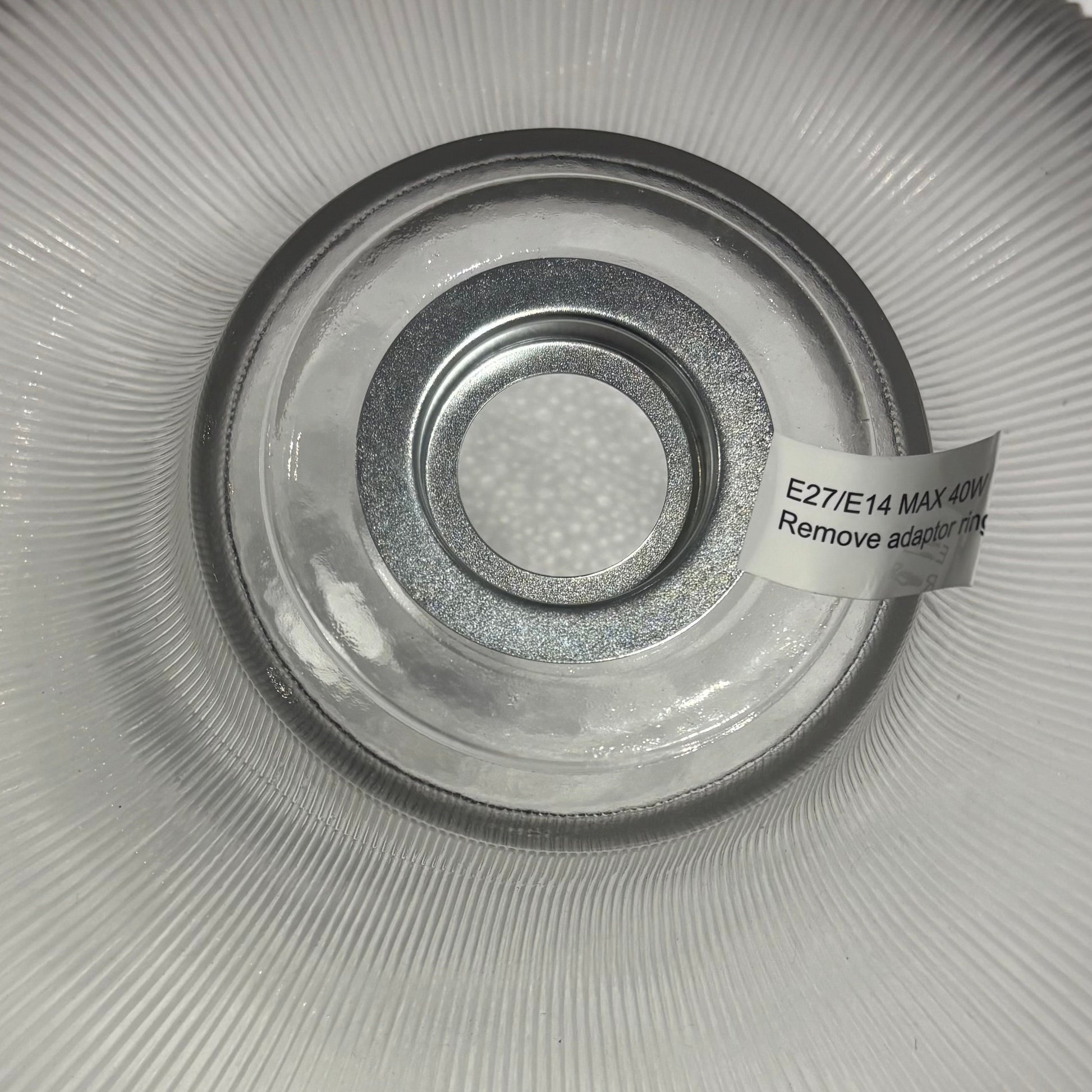 Clear glass light fixture with a label on a white background