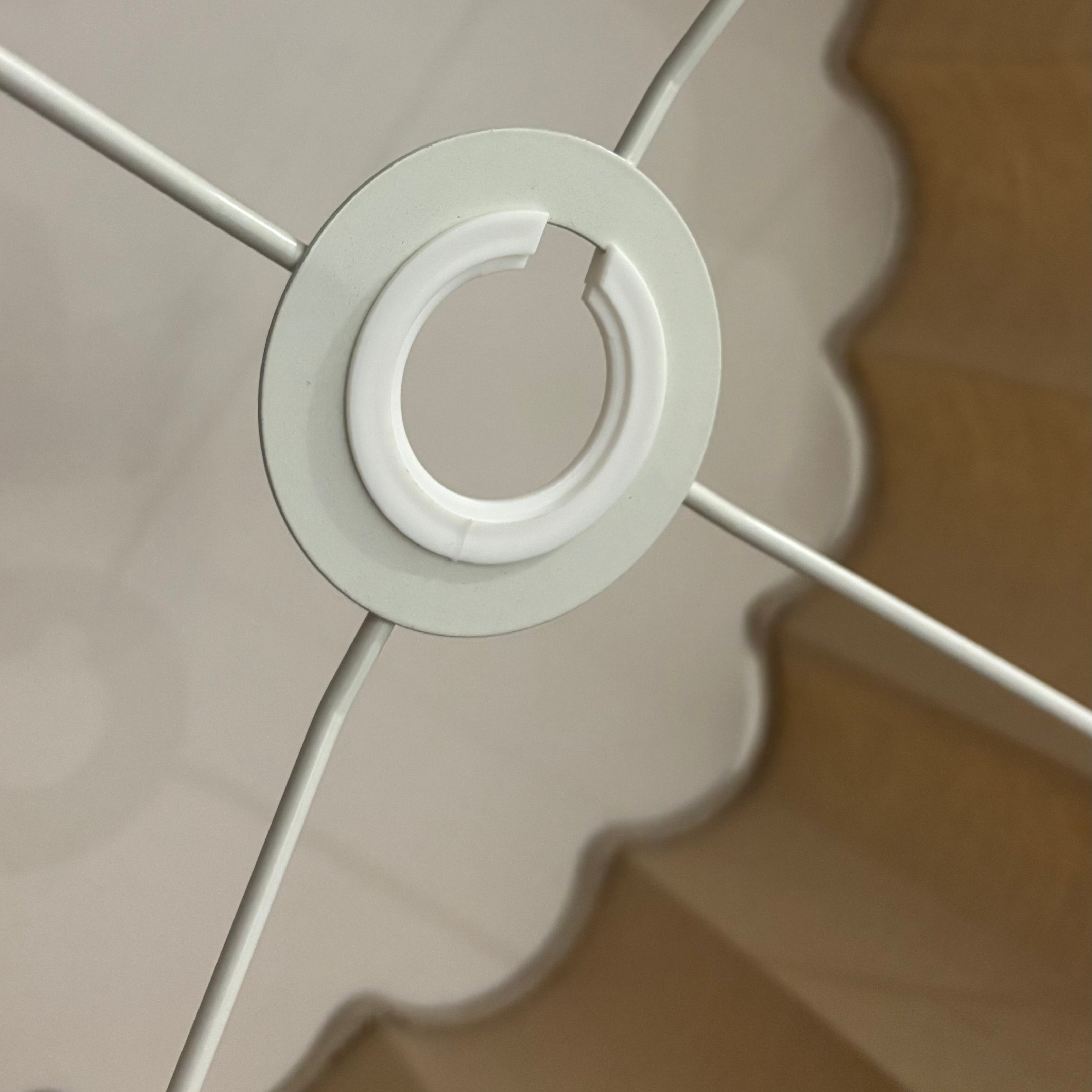 Close-up of a white ceiling light fixture with scalloped edge