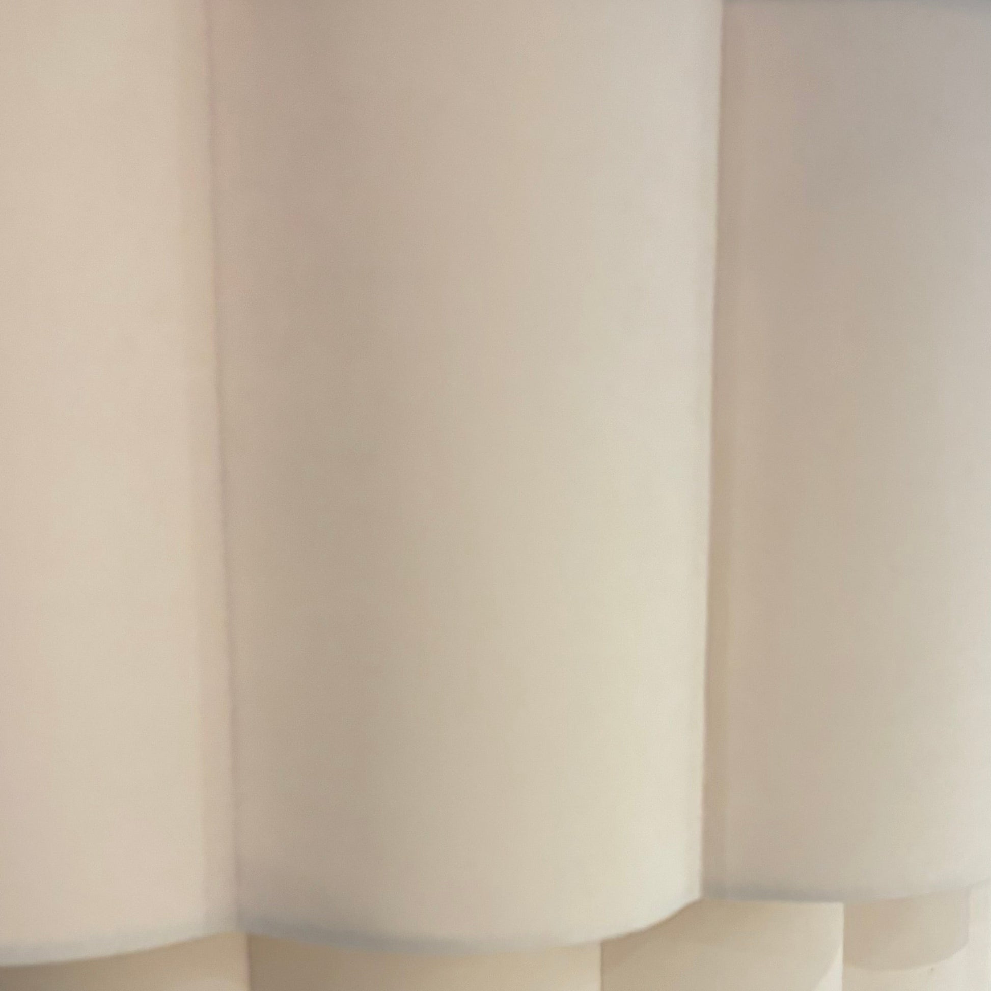 Close-up of a modern lamp with a white, fluted shade in an indoor setting.