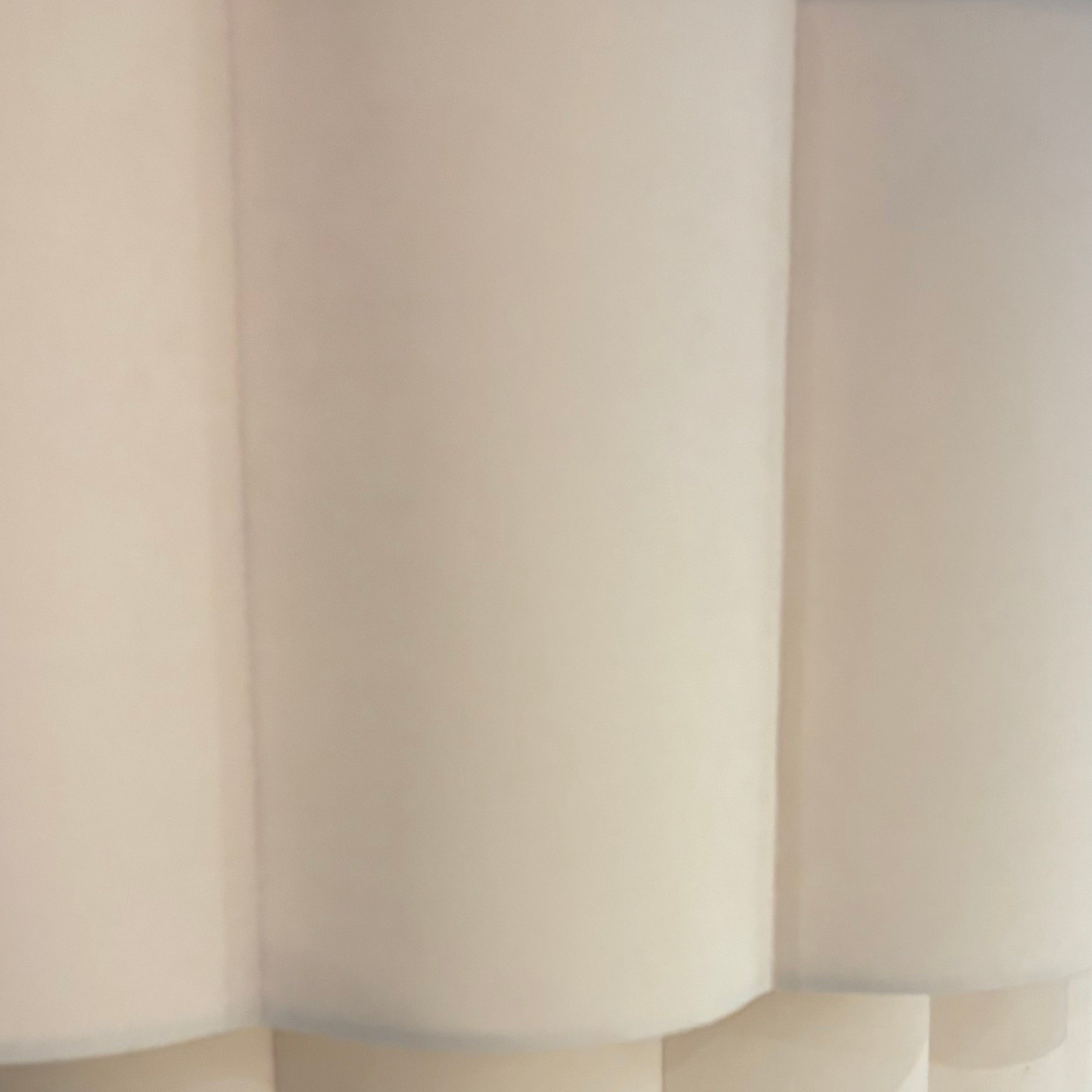 Close-up of a modern lamp with a white, fluted shade in an indoor setting.