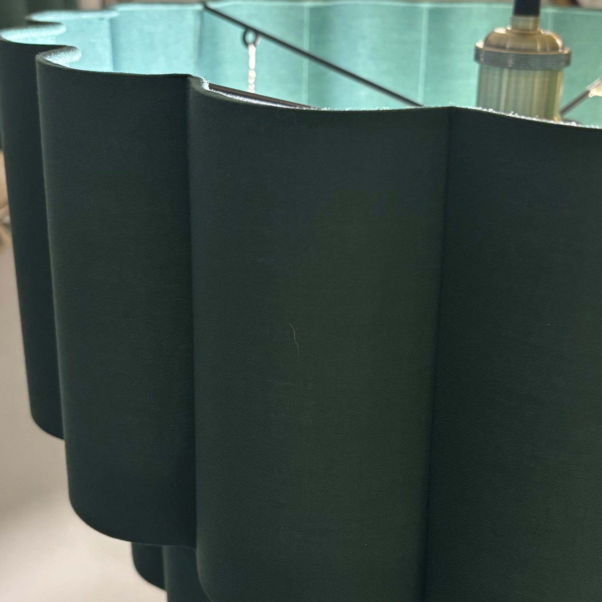 Dark green lampshade with a reflective surface on a white wall background